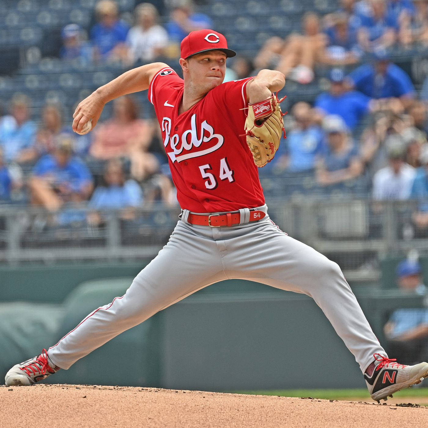Sonny Gray 跳躍投球 壁紙 — 一位身穿紅色球衣的辛辛那提紅人隊投手在陽光明媚的投手丘上投球，背景有模糊的球迷。
