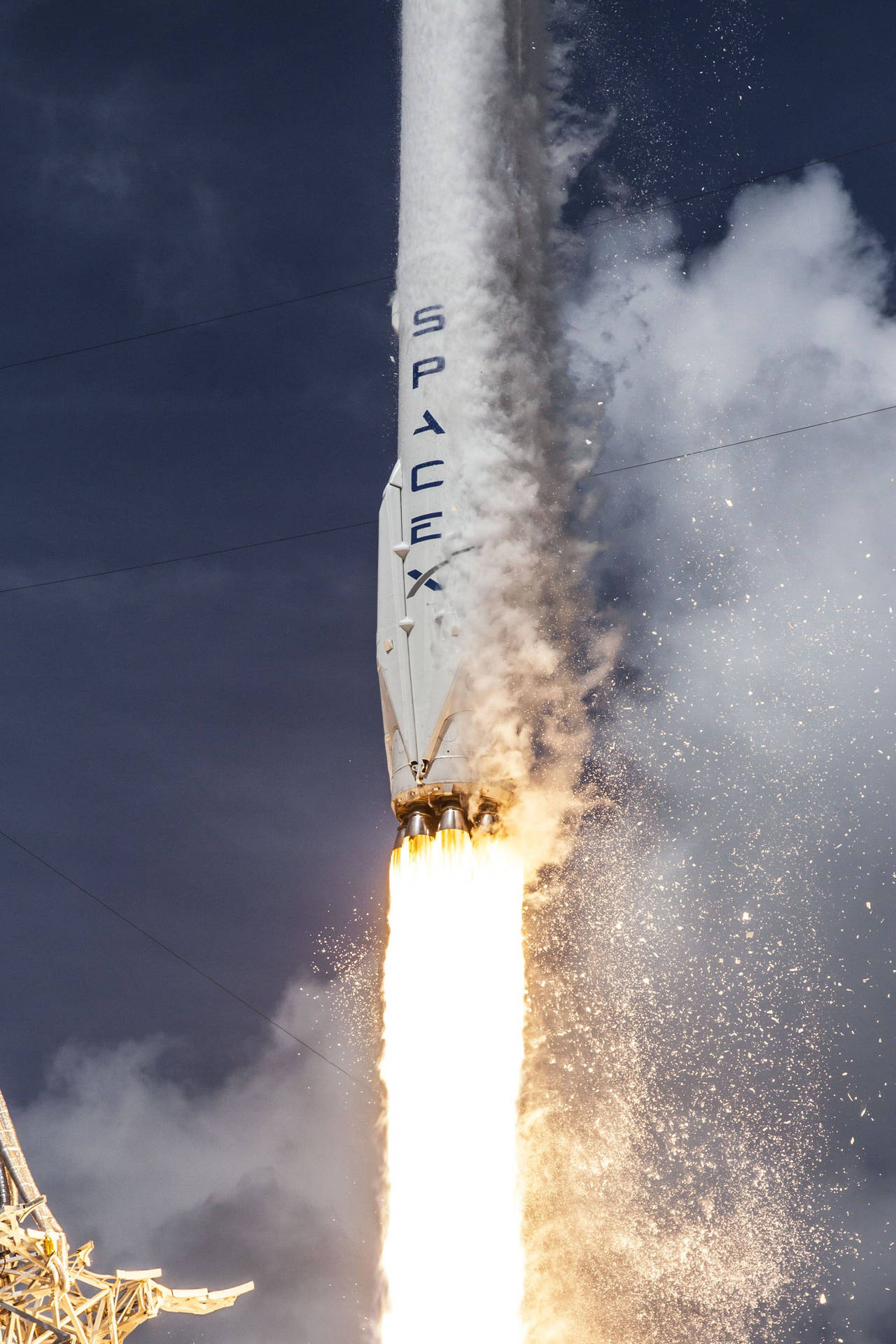 SpaceX 火箭在陰暗的天空中帶著明亮的火焰和煙霧上升。 — Spacex GIF 壁紙