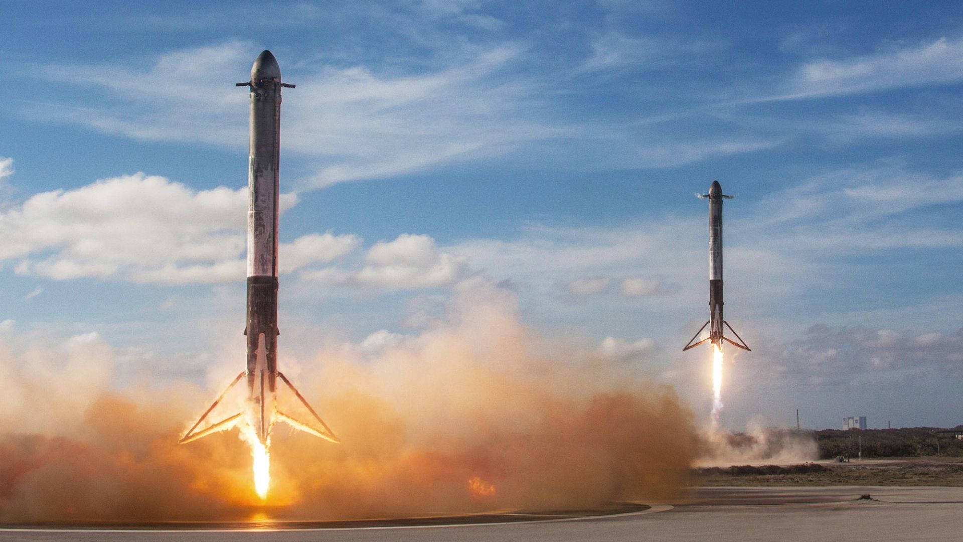 兩枚火箭在藍天白雲背景下，帶著明亮火焰發射升空。 — Spacex GIF 壁紙
