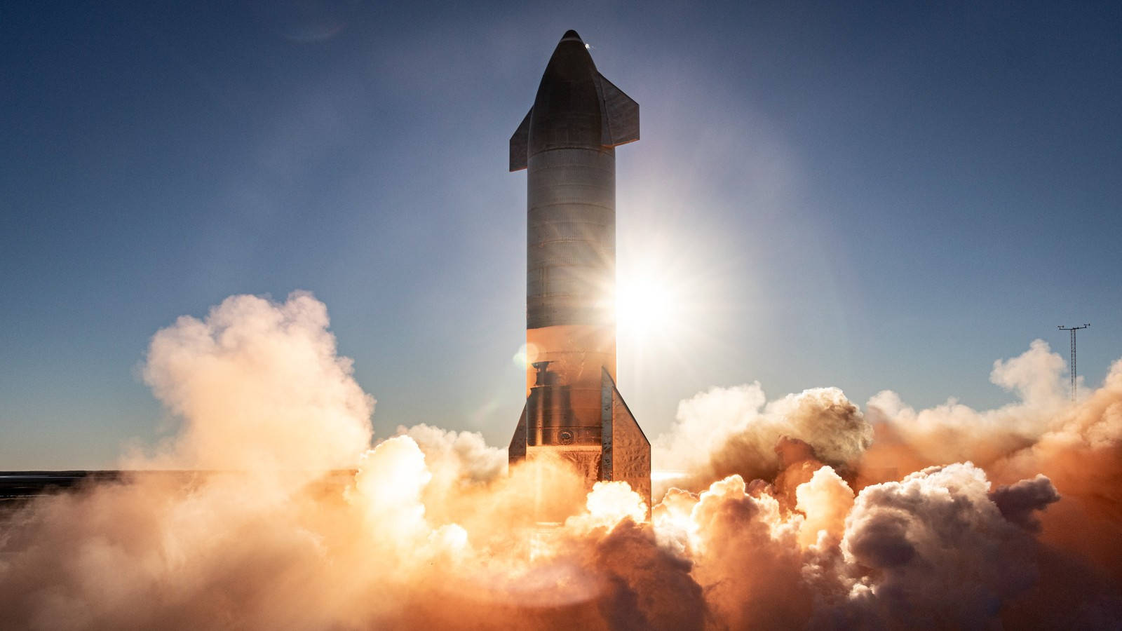 SpaceX Starship 火箭在藍天下發射，帶有熾熱的廢氣和濃煙。