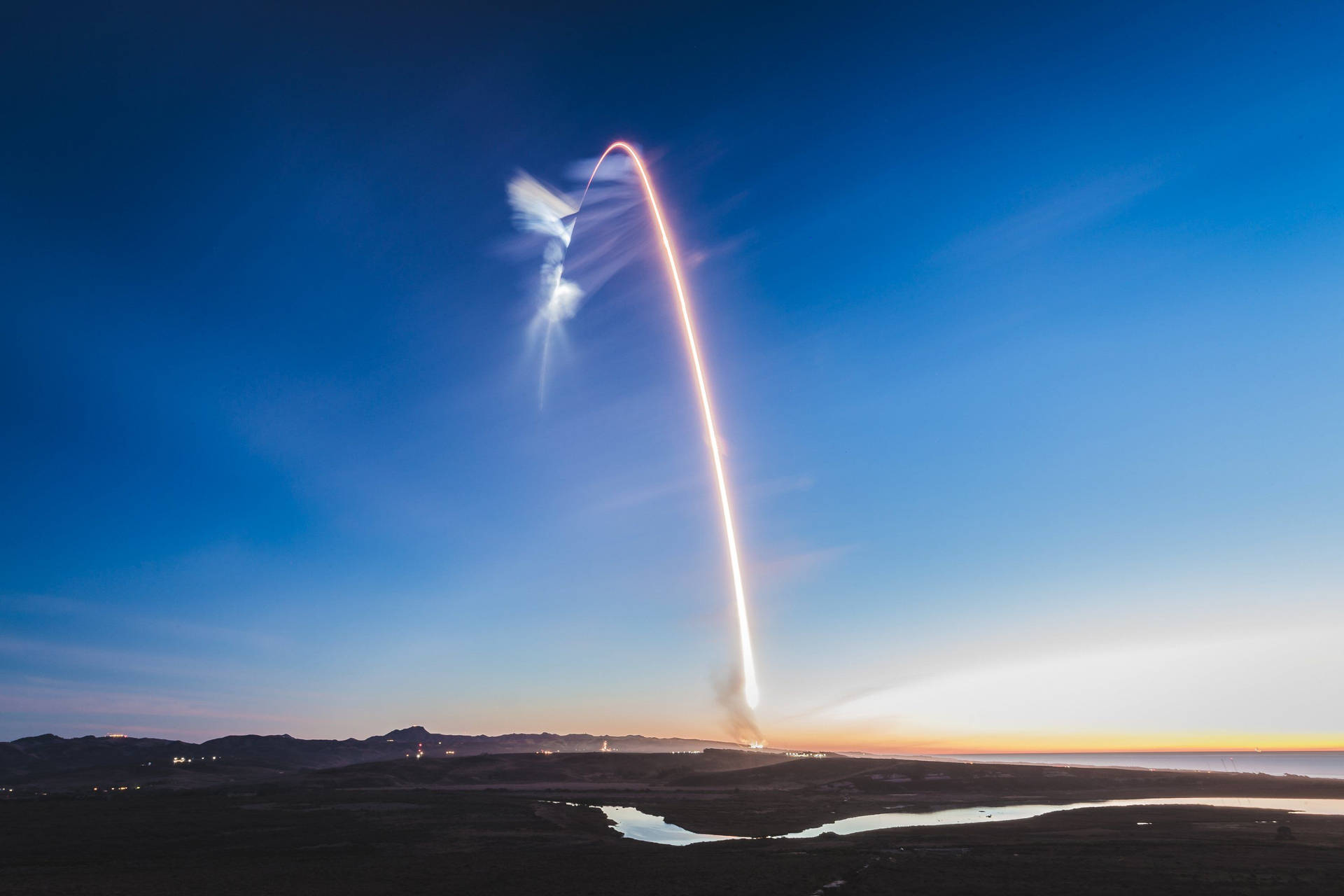 黃昏時分在沙漠、山脈和河流上空發射火箭 — Spacex GIF 壁紙