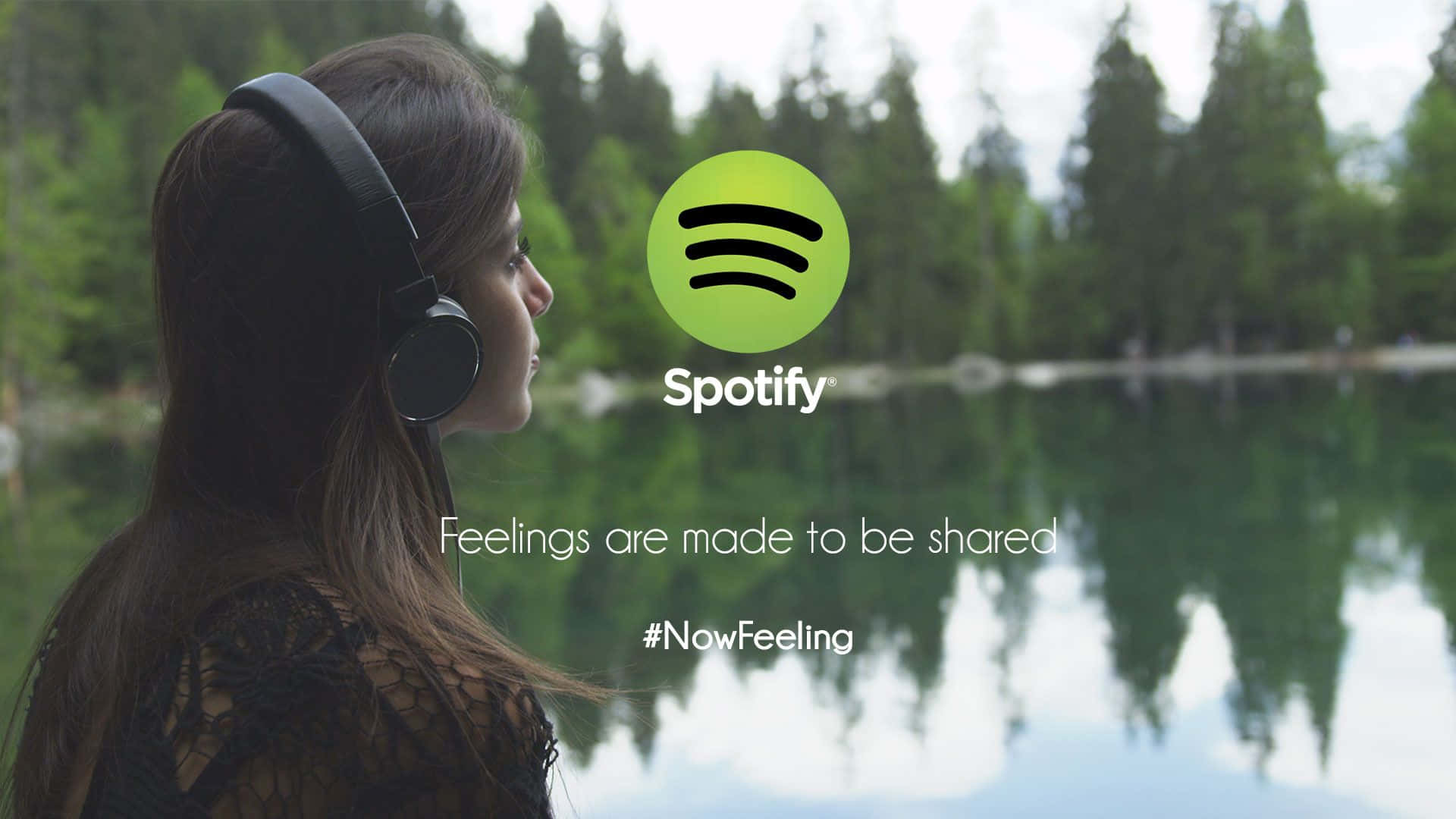 Spotify - 一位戴著耳機的女性站在湖前 壁紙