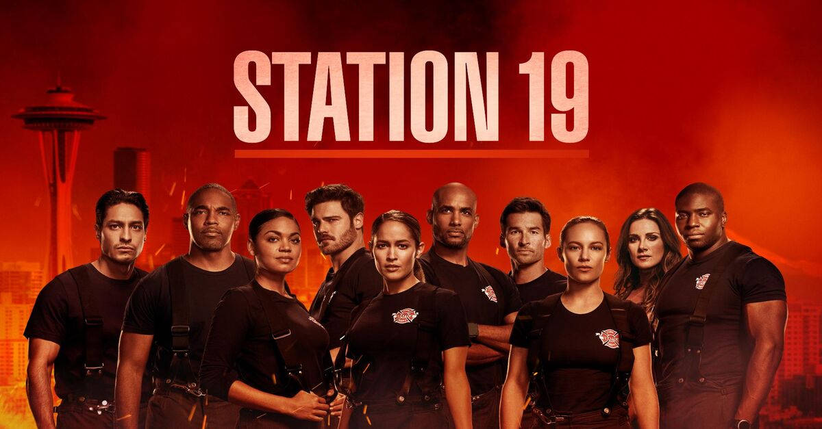 《Station 19》烈焰海報 壁紙 — 一群穿著黑色制服的消防員自信地站在火紅色的背景前，身後可見西雅圖太空針塔。