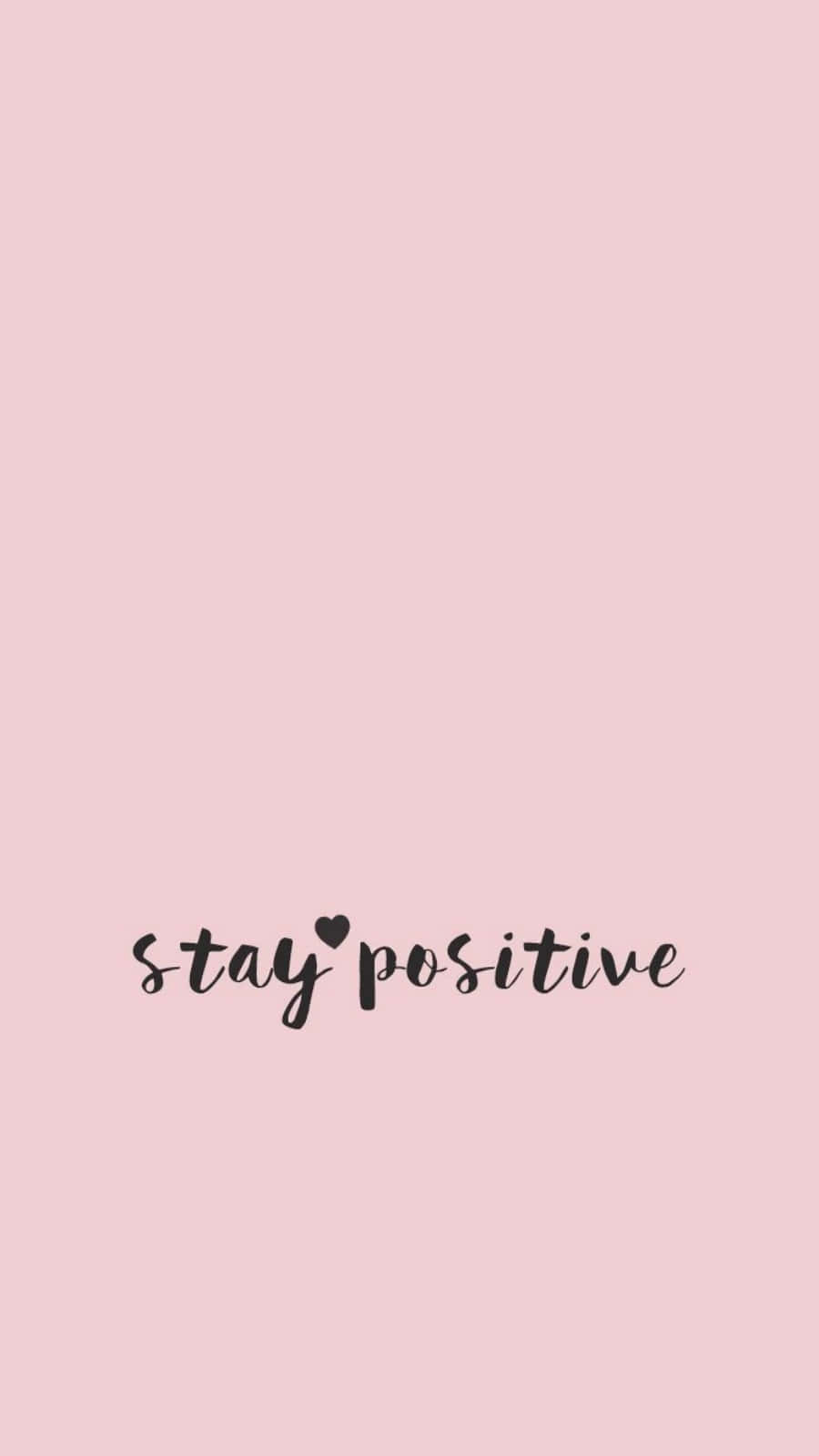 粉色背景「Stay Positive」手寫體壁紙 壁紙 — 柔和粉紅色背景，黑色草書文字寫著 stay positive，並用心形取代字母 i 上方的點。