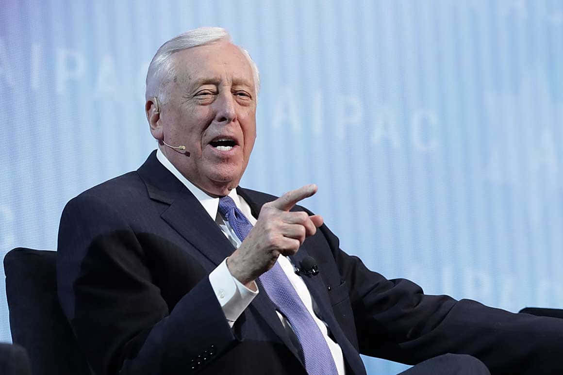 Steny Hoyer 深度參與討論 壁紙 — 一位身穿深色西裝和紫色領帶的年長男性，在淺藍色背景的正式活動中說話時，用力地做手勢。