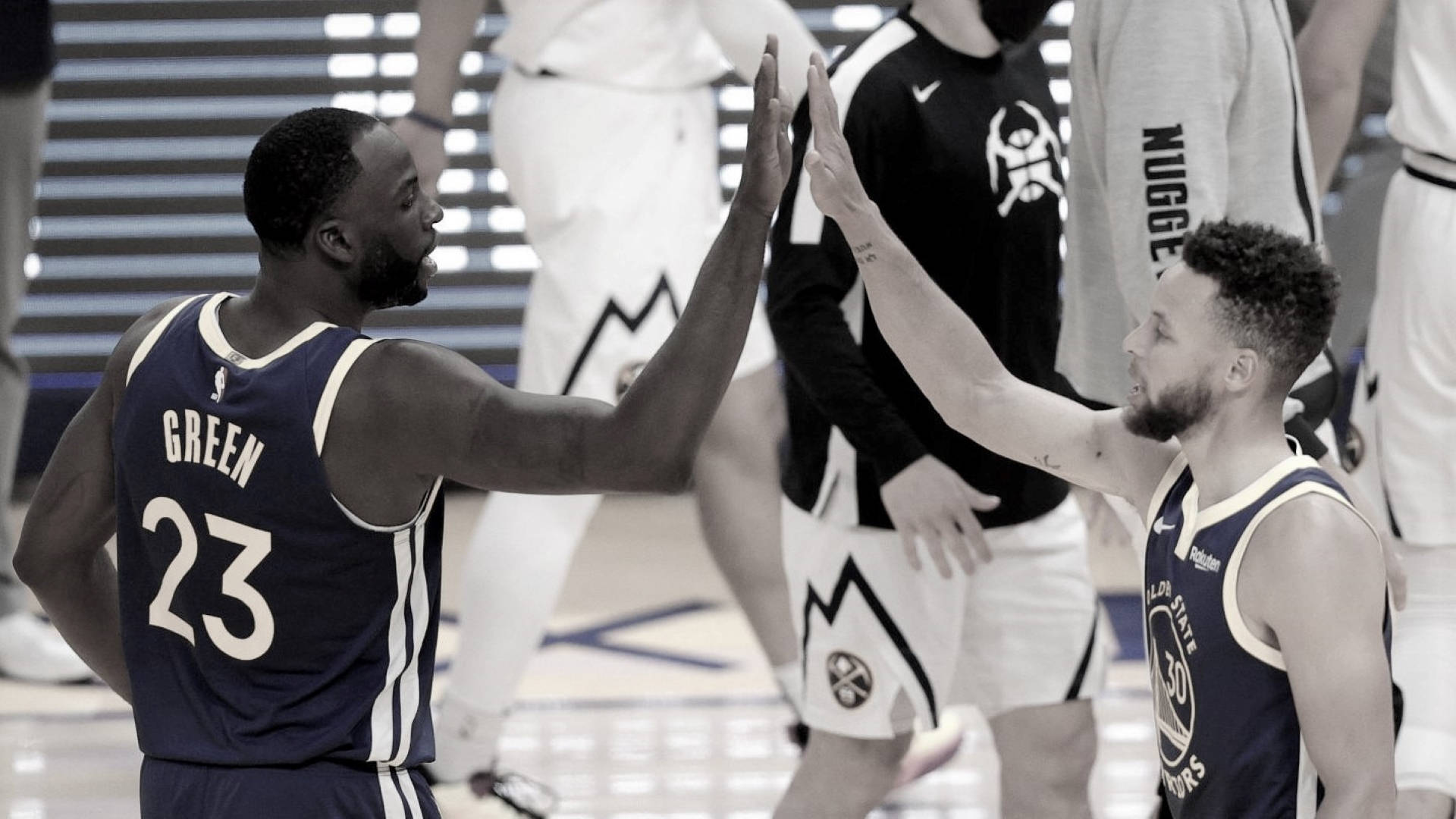 Steph Curry 與 Draymond Green 高五慶功照 壁紙 — 兩名身穿海軍藍球衣的籃球運動員在球場上擊掌，背景有隊友。