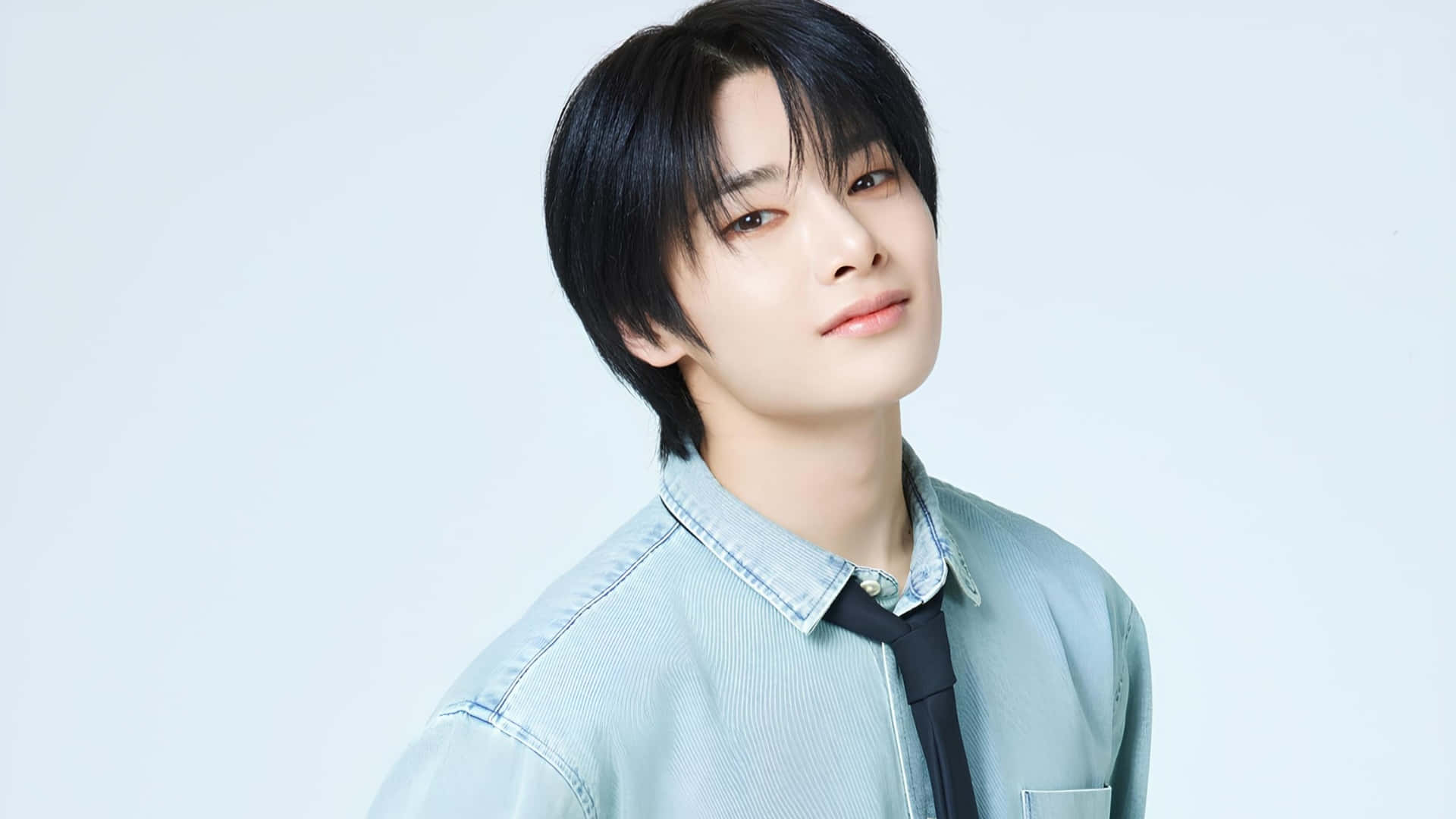 Stray Kids I.N 人物照 壁紙 — 一位深色頭髮的年輕男士穿著淺藍色牛仔襯衫和黑色領帶，背景為柔和的白色。
