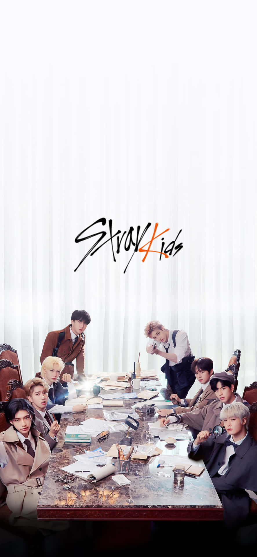 Stray Kids 在工作室環境中圍繞凌亂桌子的團體照。