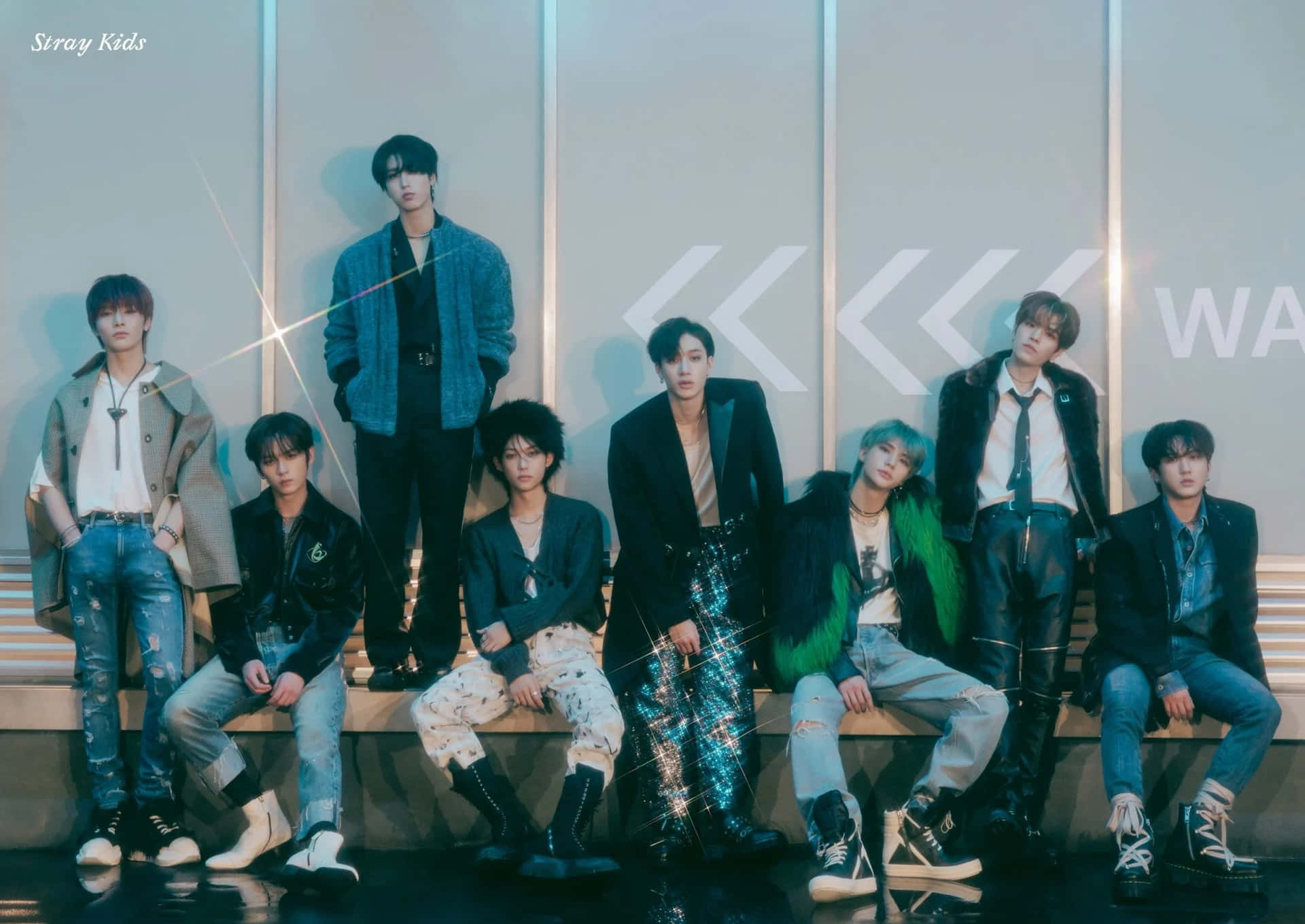 Stray Kids 穿著時尚服裝在舞台上擺姿勢，身後有發光的燈光。 — Stray kids GIF 壁紙