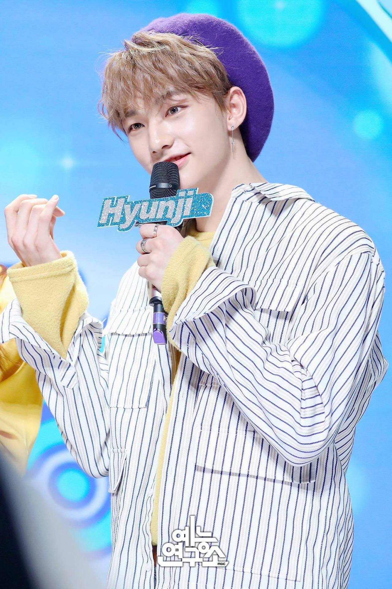 K-pop表演者在舞台上微笑著拿著麥克風。
