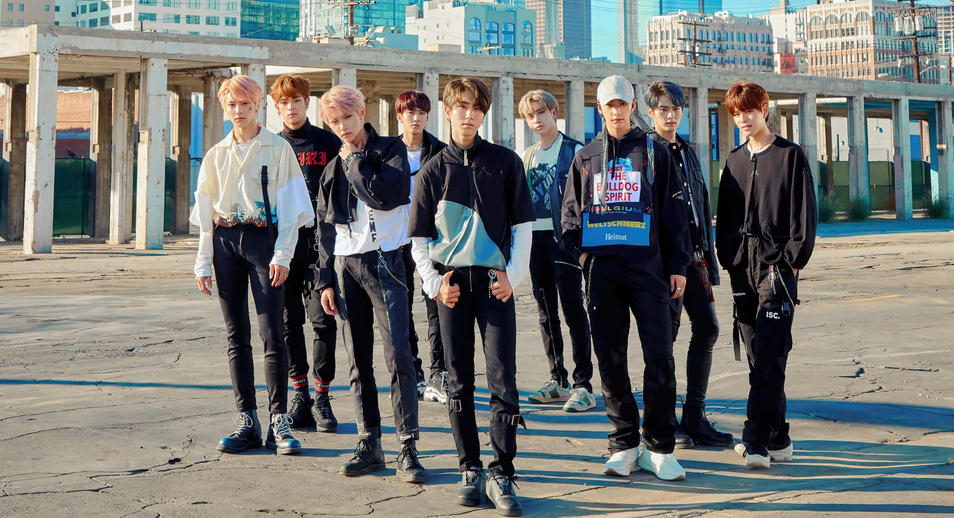 七位年輕男士身穿潮流街頭服裝，站在城市建築工地。 — Stray kids GIF 壁紙