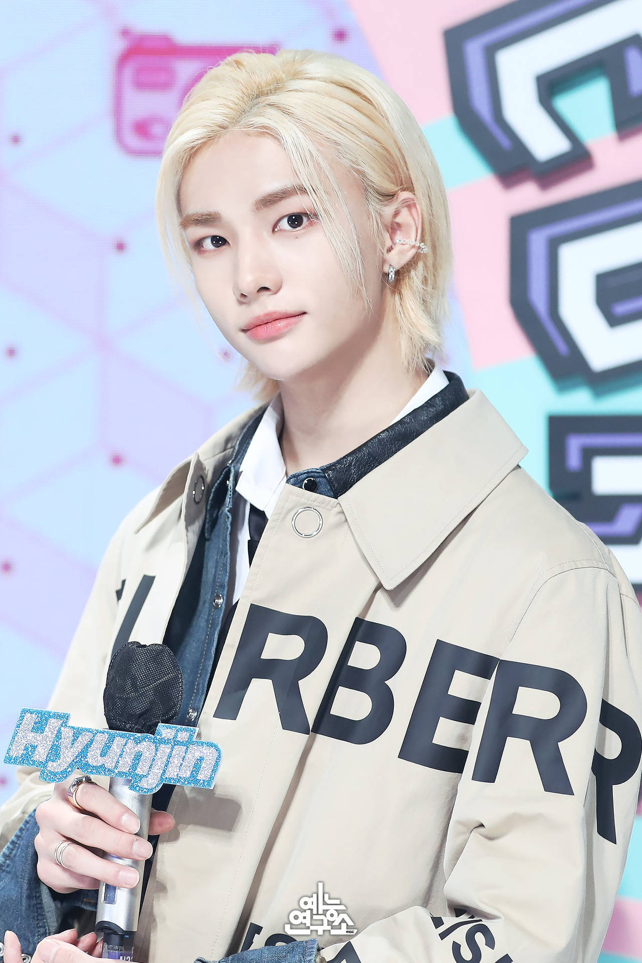 K-pop藝人Hyunjin身穿米色Burberry外套在活動中手持麥克風。