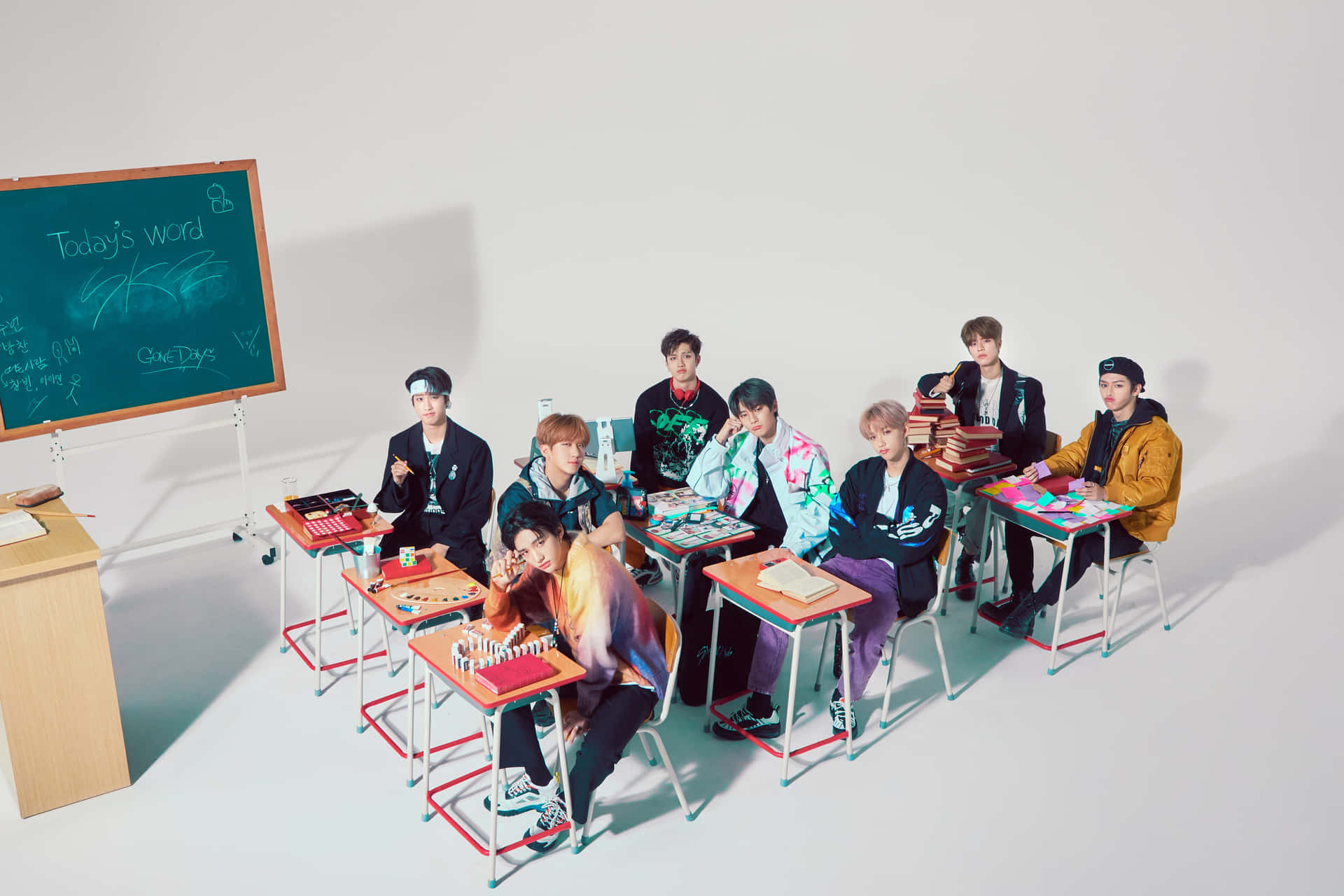 七位K-pop偶像在課室中，有書桌和黑板。