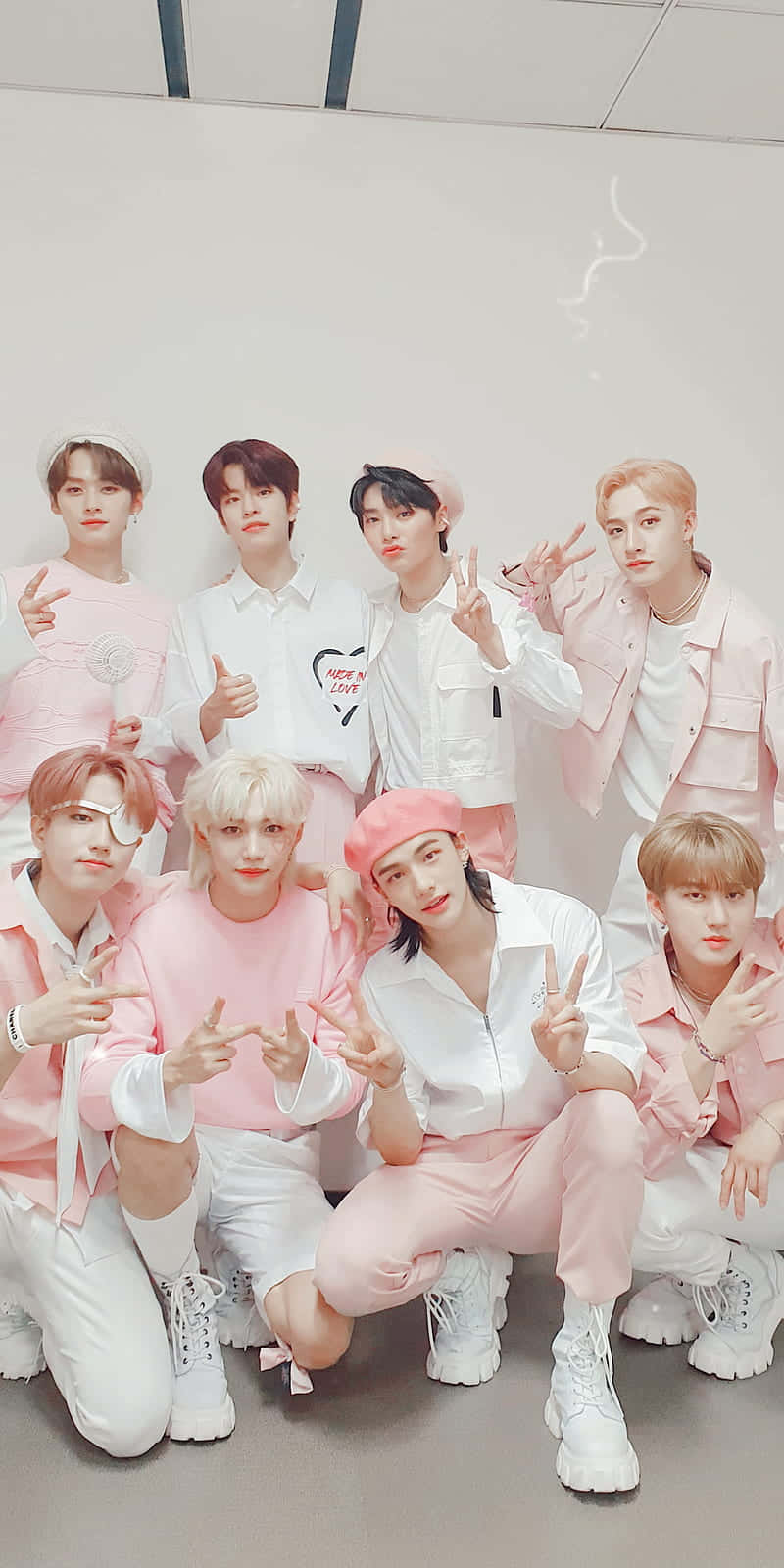 K-pop 團體在室內穿著粉紅色和白色服裝擺姿勢。