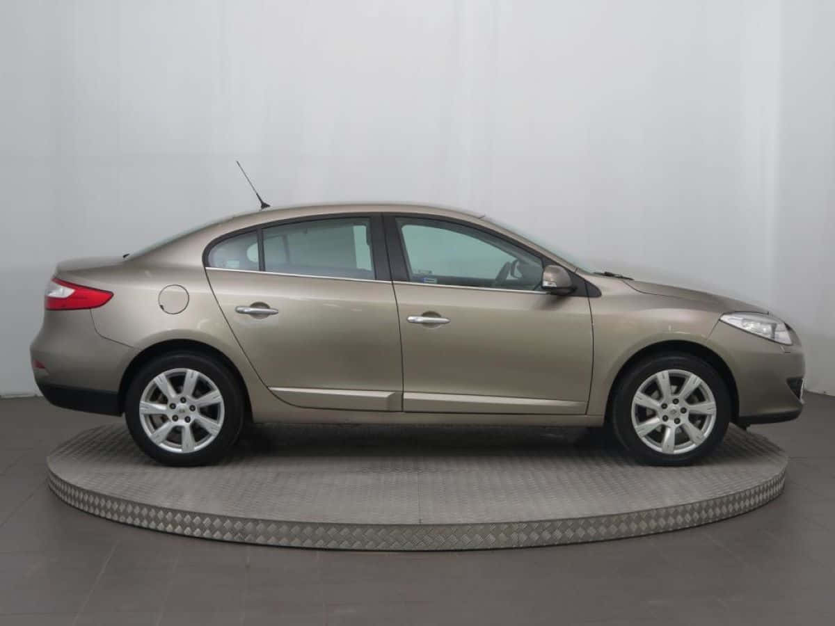 Renault Fluence 桌布 壁紙 — 一輛時尚的米色轎車在圓形金屬平台上以側面展示，背景是純白色工作室牆壁。