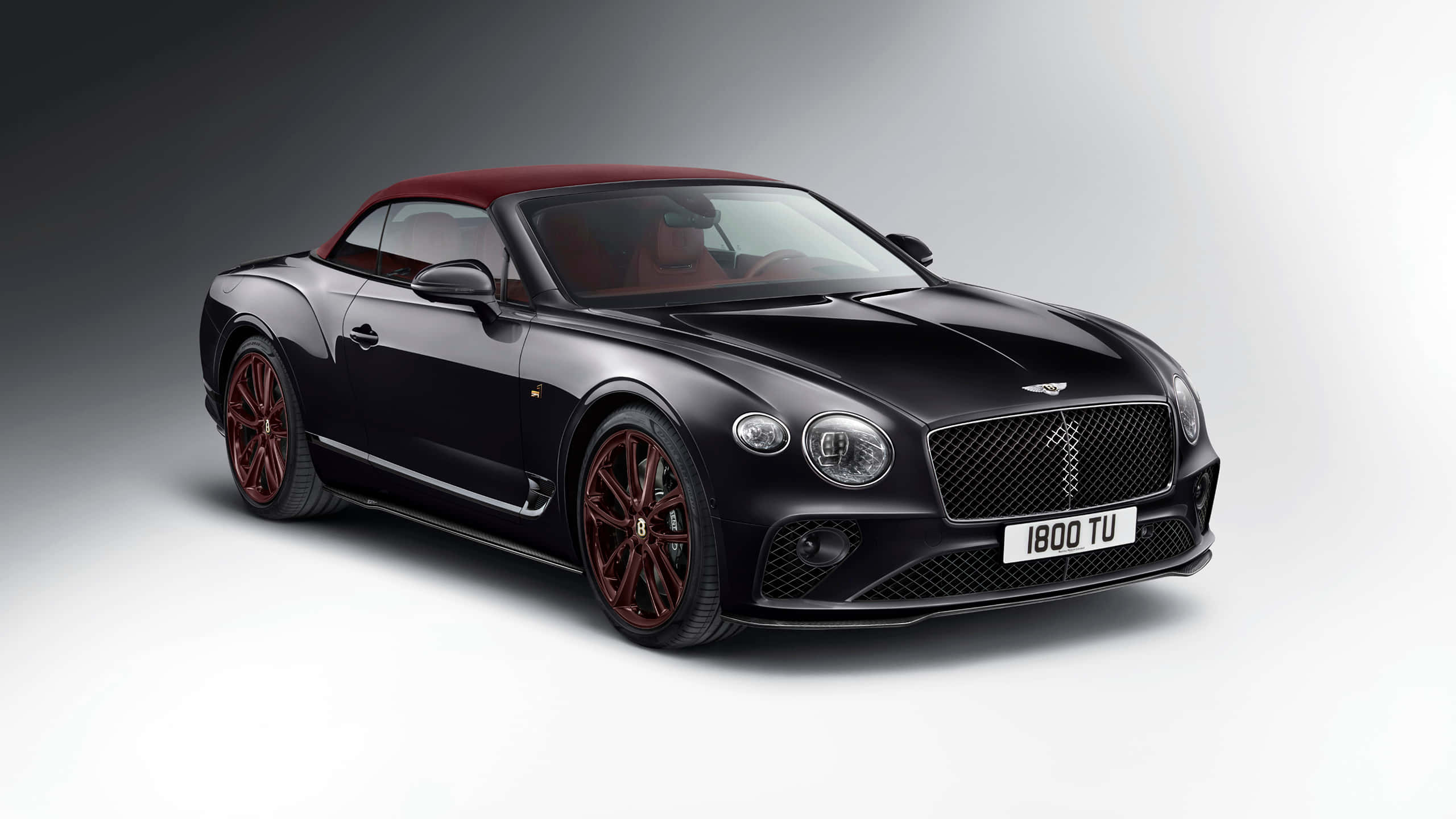 Bentley Continental Gt 桌布 壁紙 — 一輛時尚的黑色賓利敞篷車，配備紅色軟頂和相配的紅色輪圈，在簡約的工作室背景下展示。