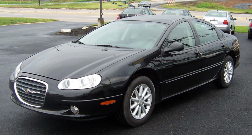 Chrysler Lhs 桌布 壁紙 — 一輛時尚的黑色克萊斯勒轎車停放在濕漉漉的瀝青停車場，旁邊有其他車輛和草地背景。