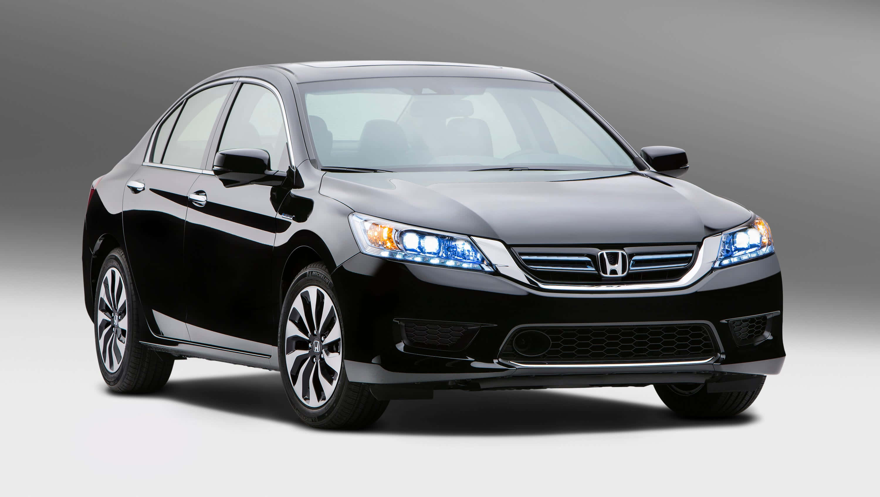 Honda Accord 桌布 壁紙 — 一輛時尚的黑色本田雅閣轎車，配備發光藍色頭燈，在漸變灰色工作室背景前展示。