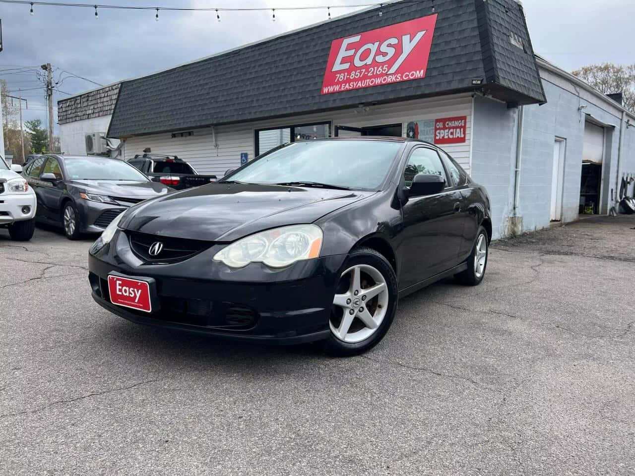 Acura Rsx 桌布 壁紙 — 一架型格黑色本田轎跑車停泊在紅色招牌的汽車修理店前，天色陰沉。