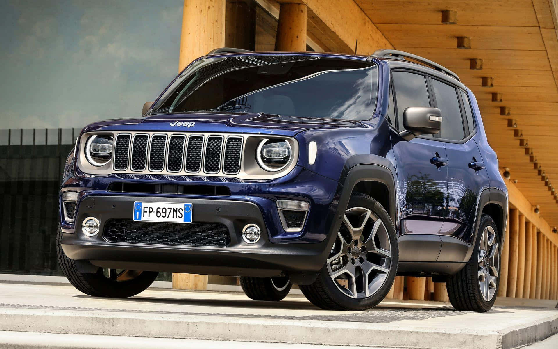 Jeep Renegade 桌布 壁紙 — 一架時尚的藍色Jeep Renegade SUV停泊在混凝土平台上，旁邊是木樓梯，天空多雲。