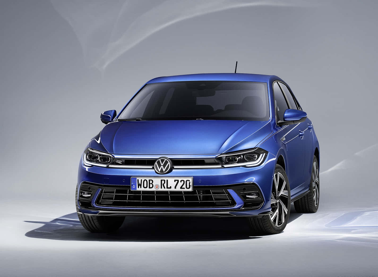 Volkswagen Polo 桌布 壁紙 — 時尚的藍色福士 Polo R-Line 房車在簡約灰色背景前於攝影棚燈光下閃耀。