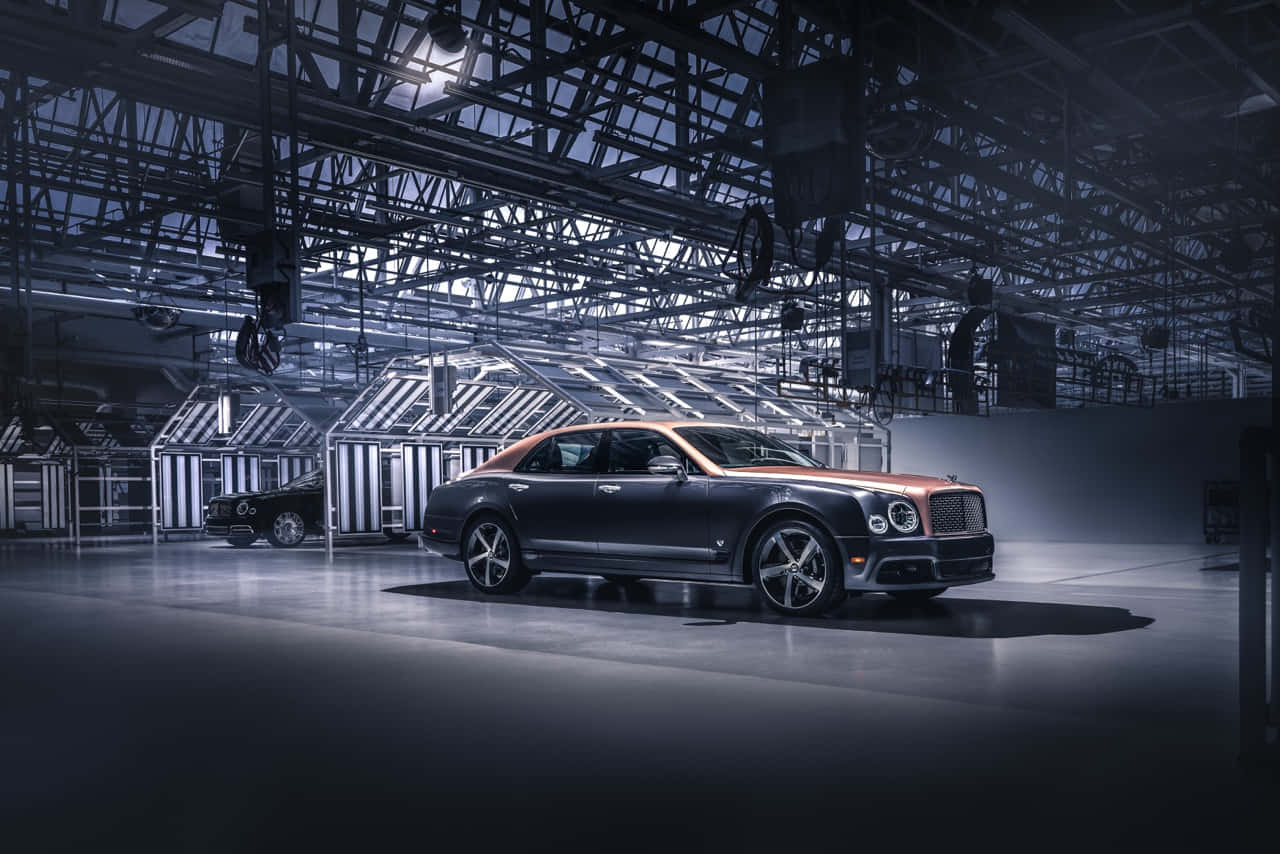 Bentley Mulsanne 桌布 壁紙 — 一輛時尚的深色賓利轎車，配備銅製車頂，在寬敞的工廠環境中，在工業燈光下閃閃發光。