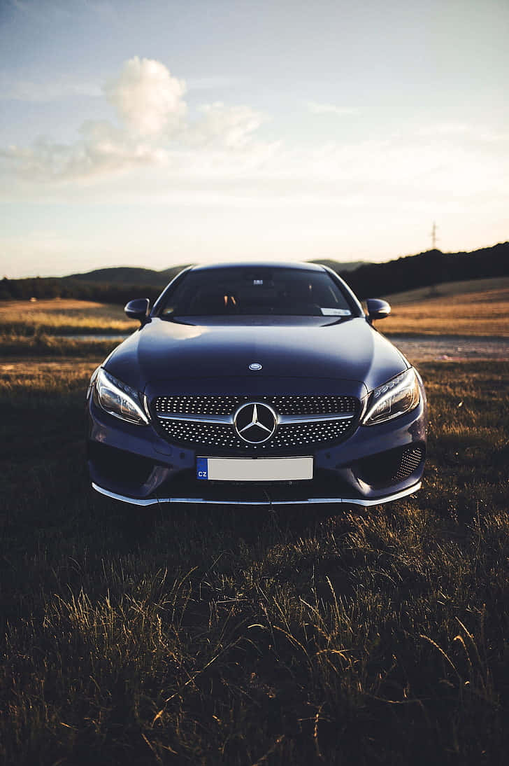 Mercedes Benz Cls-class 桌布 壁紙 — 一輛時尚的深藍色平治房車停泊在日落時分的金色田野中，背景是連綿起伏的山丘。