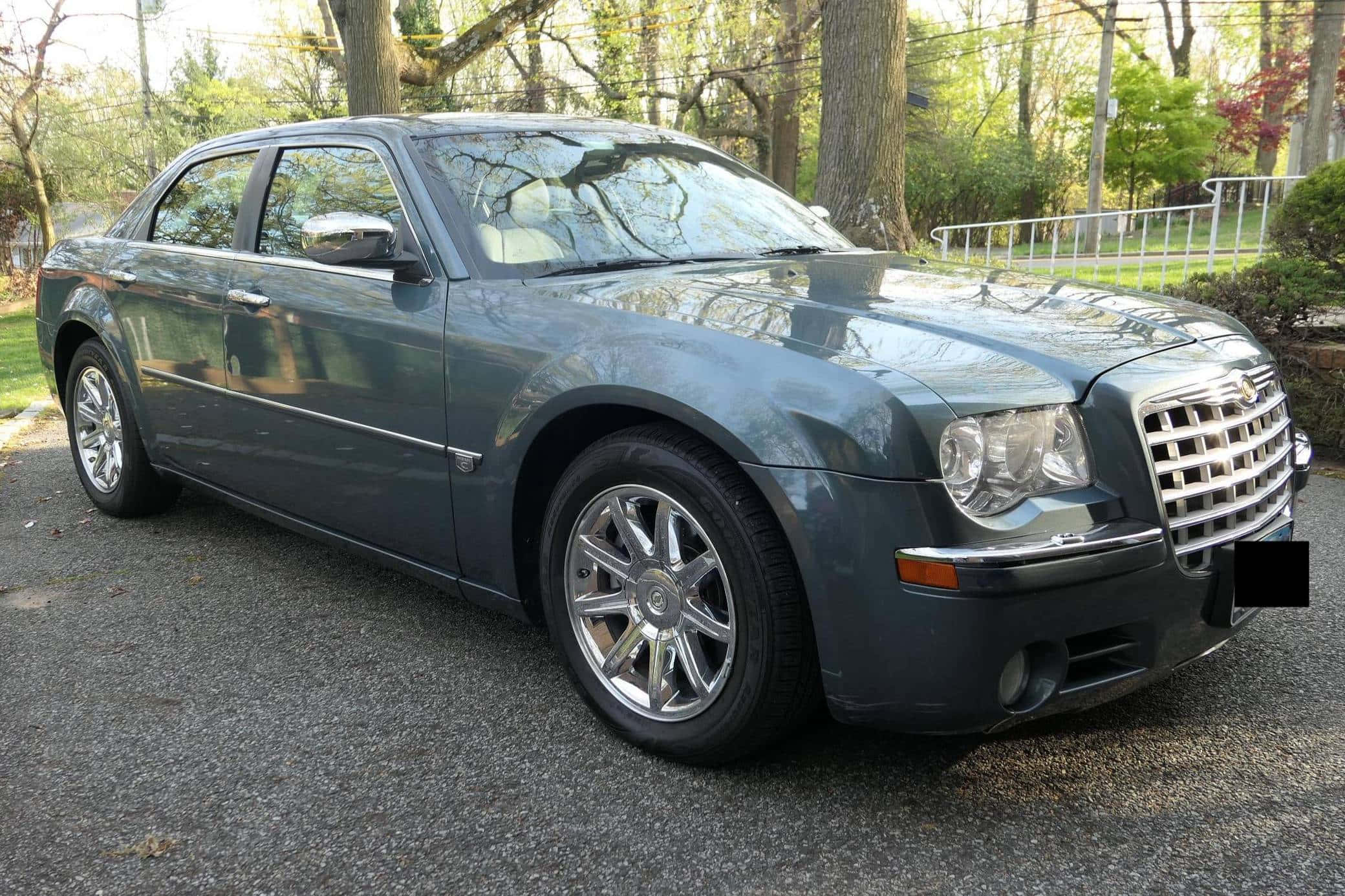 Chrysler 300 桌布 壁紙 — 一架時尚的灰色 Chrysler 300 房車停泊在碎石車道上，周圍環繞著樹木和綠植。