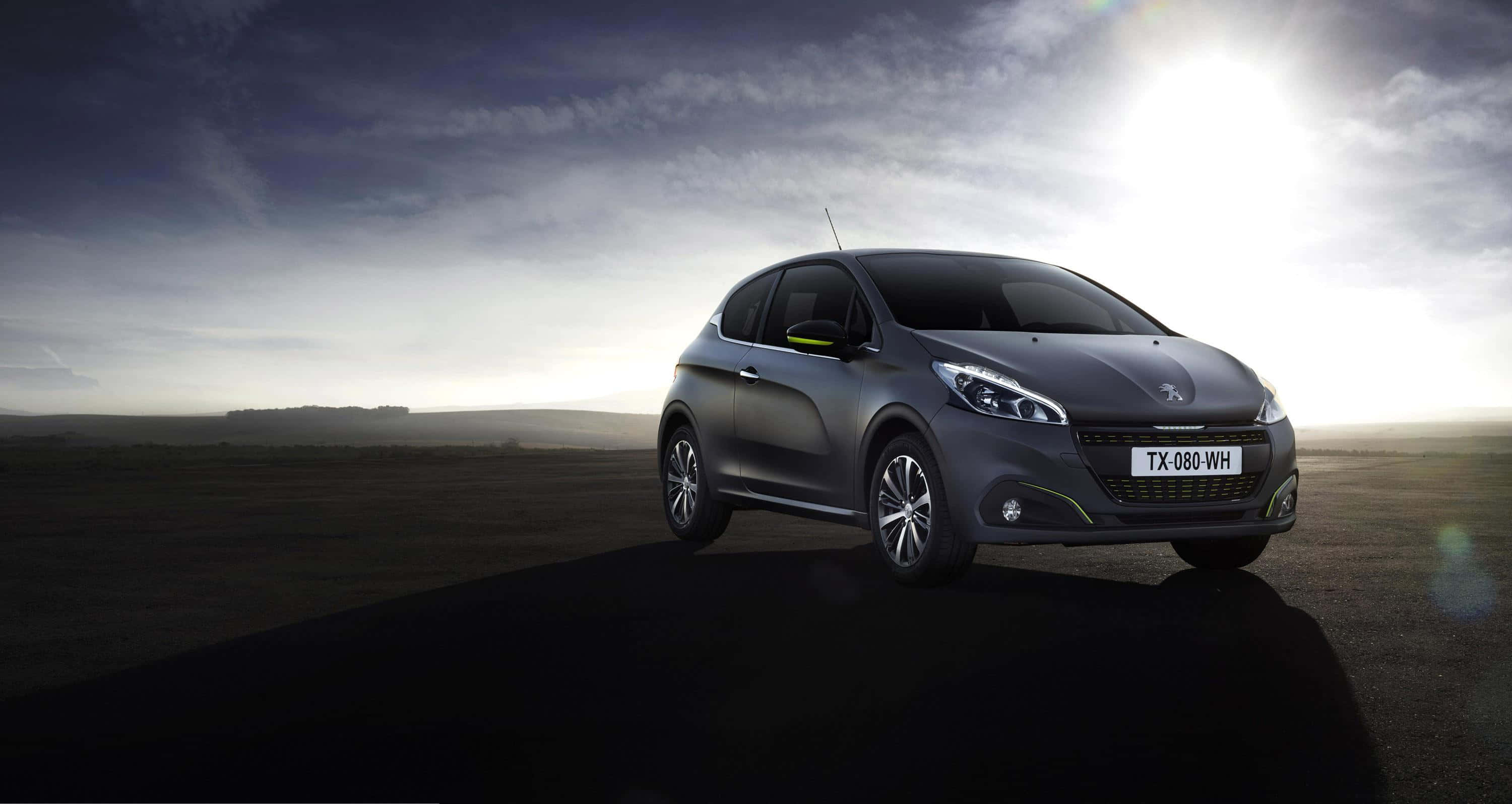 Peugeot 208 桌布 壁紙 — 一輛時尚的灰色掀背車在陰暗的道路上，背景是戲劇性的多雲天空和明亮的太陽光暈。
