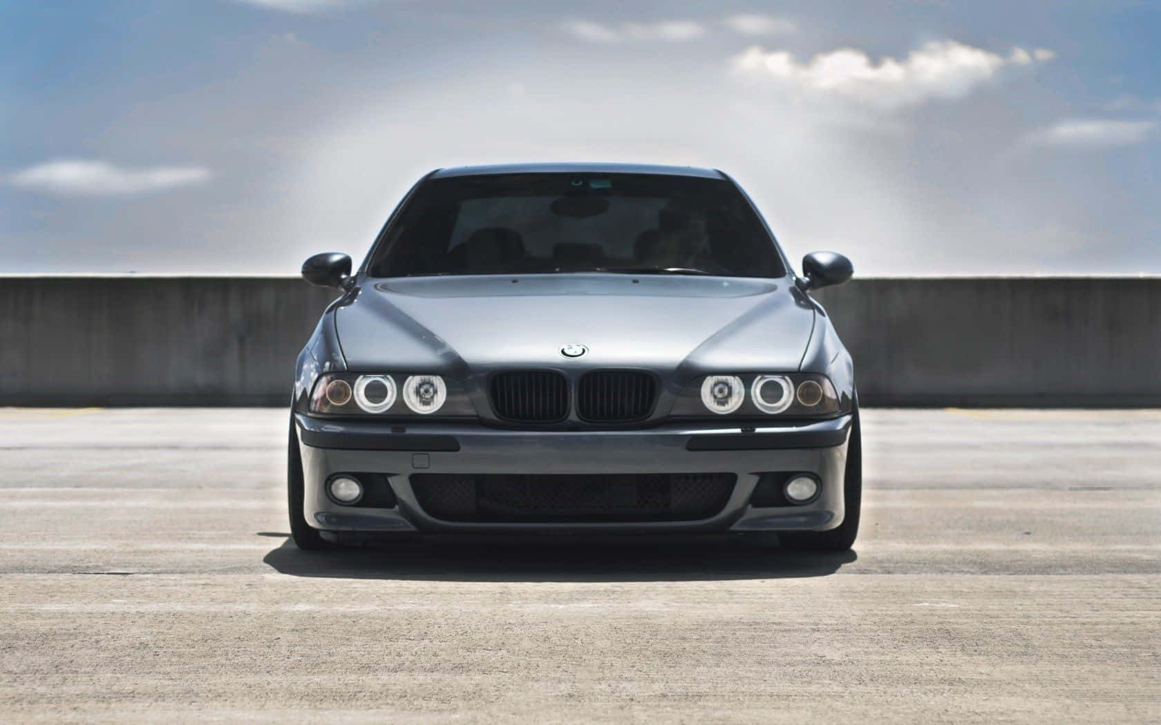 Bmw M5 桌布 壁紙 — 一部時尚的銀色寶馬E39房車在部分多雲的天空下，正面朝前停在混凝土表面上。