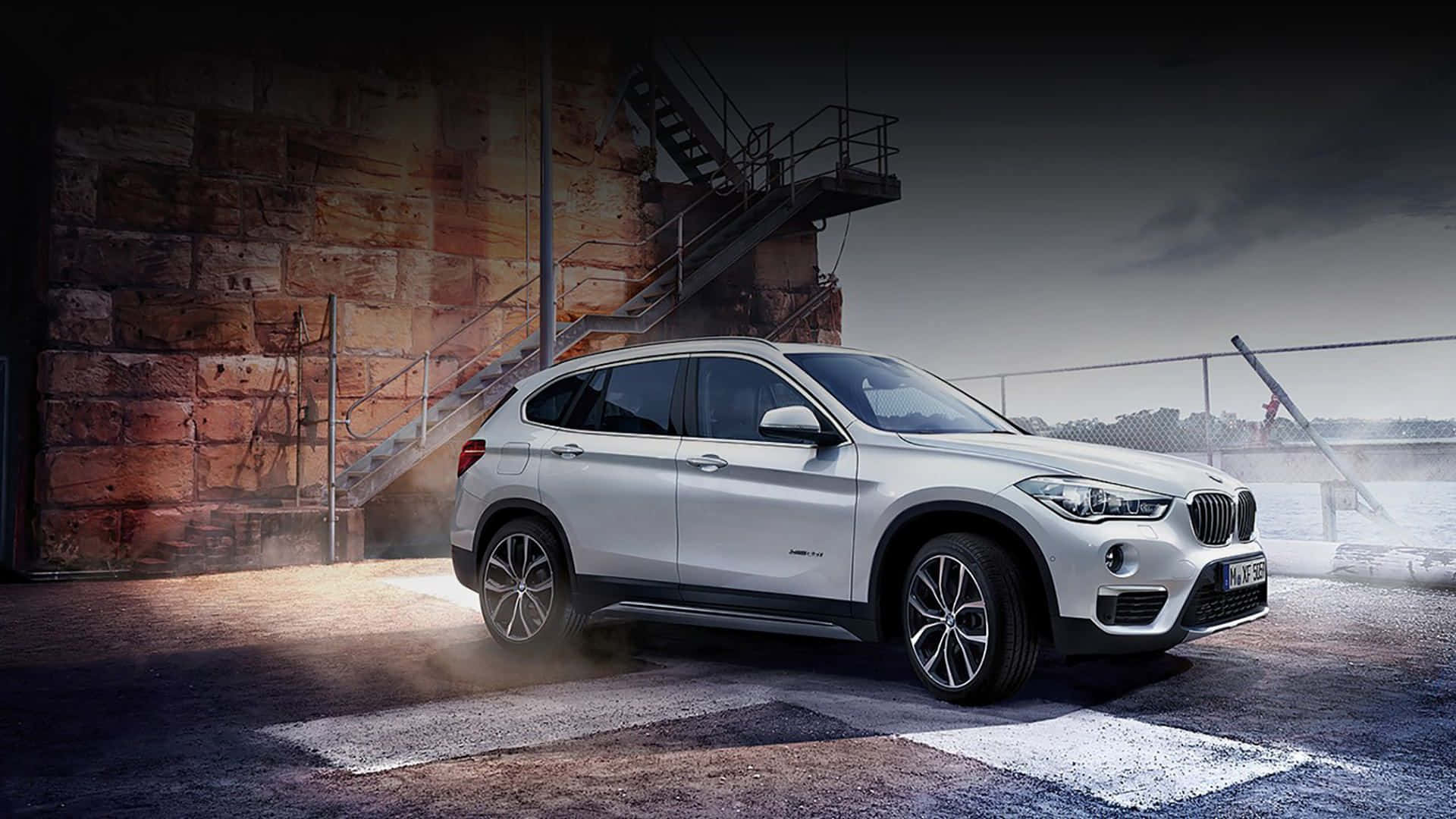 Bmw I8 桌布 壁紙 — 一輛時尚的銀色BMW X1 SUV在黃昏時停泊在粗糙的工業碼頭，蒸汽升騰，燈光戲劇化。