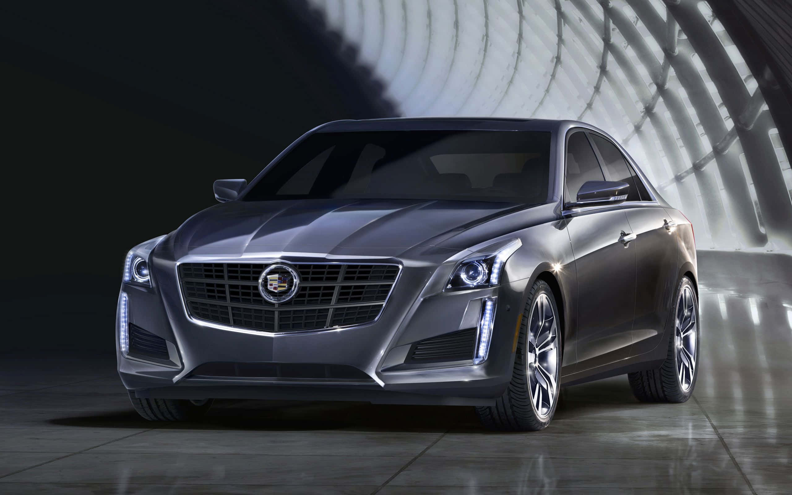 Cadillac Cts 桌布 壁紙 — 一輛時尚的銀色凱迪拉克轎車在彎曲隧道狀結構內的戲劇性工作室燈光下閃閃發光。