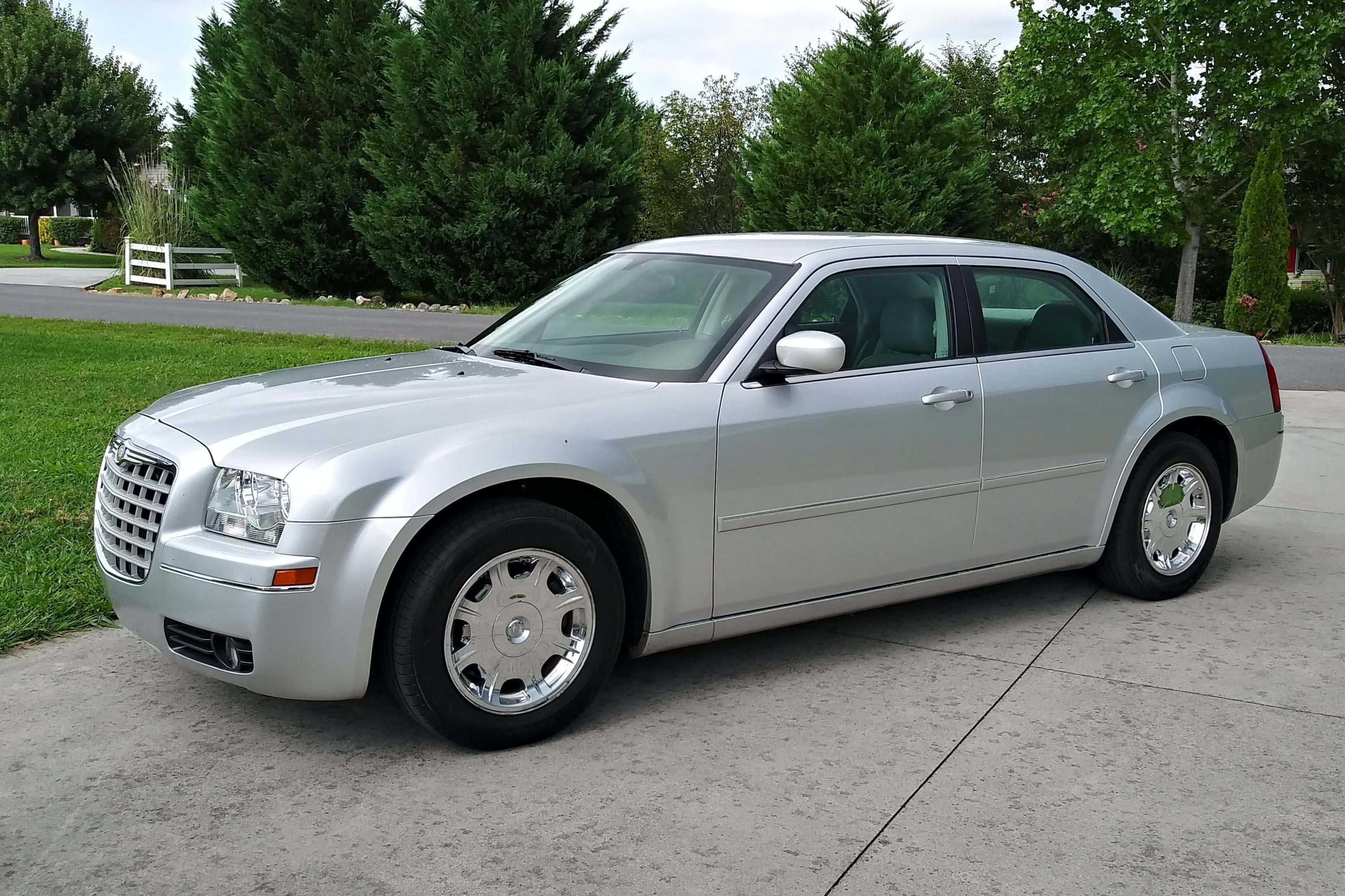 Chrysler 300 桌布 壁紙 — 一架時尚的銀色Chrysler 300房車停在混凝土車道上，背景有綠樹和草地。