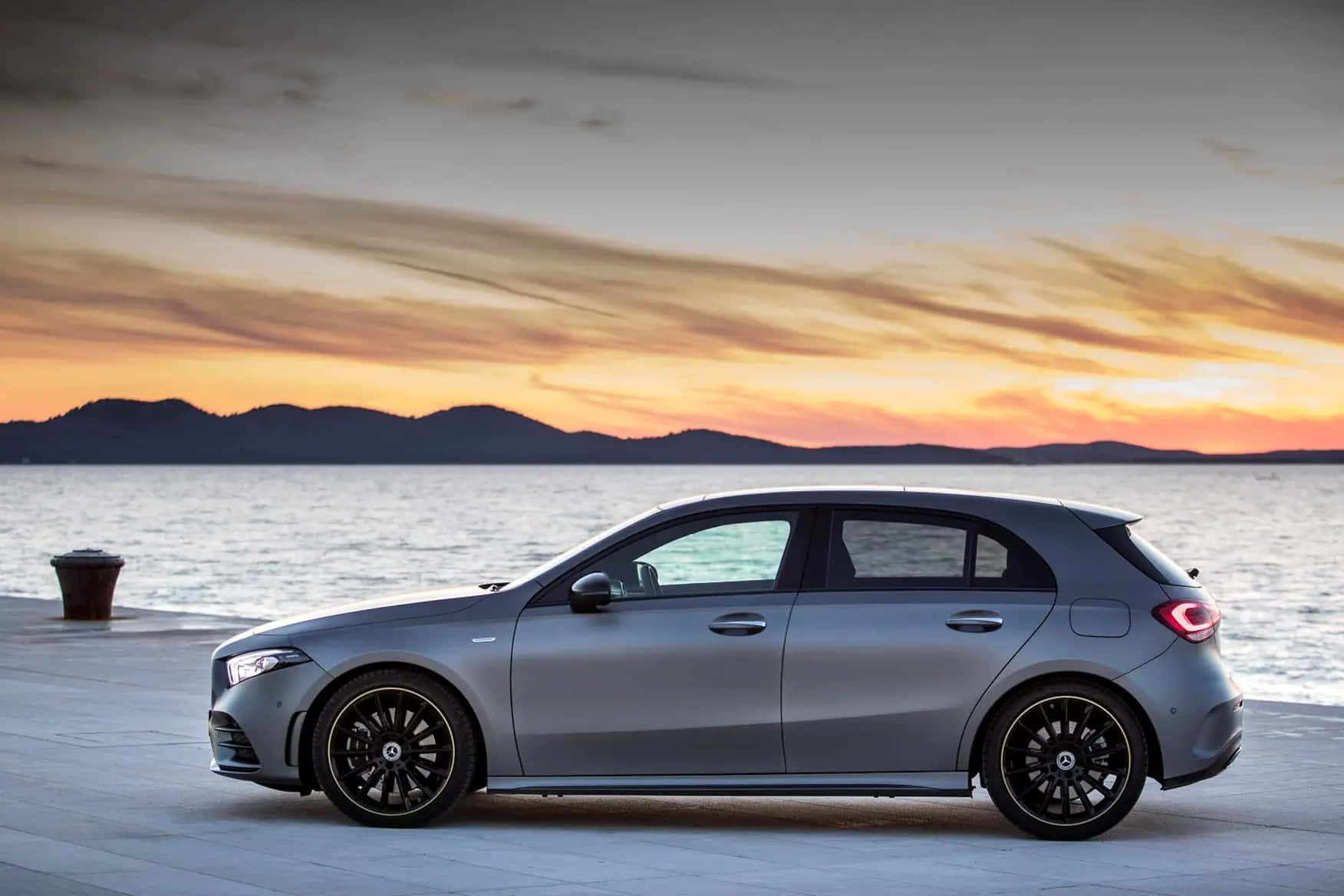 Mercedes Benz A-class 桌布 壁紙 — 一架時尚的銀色掀背車停泊在海濱碼頭上，夕陽西下，遠山如黛。