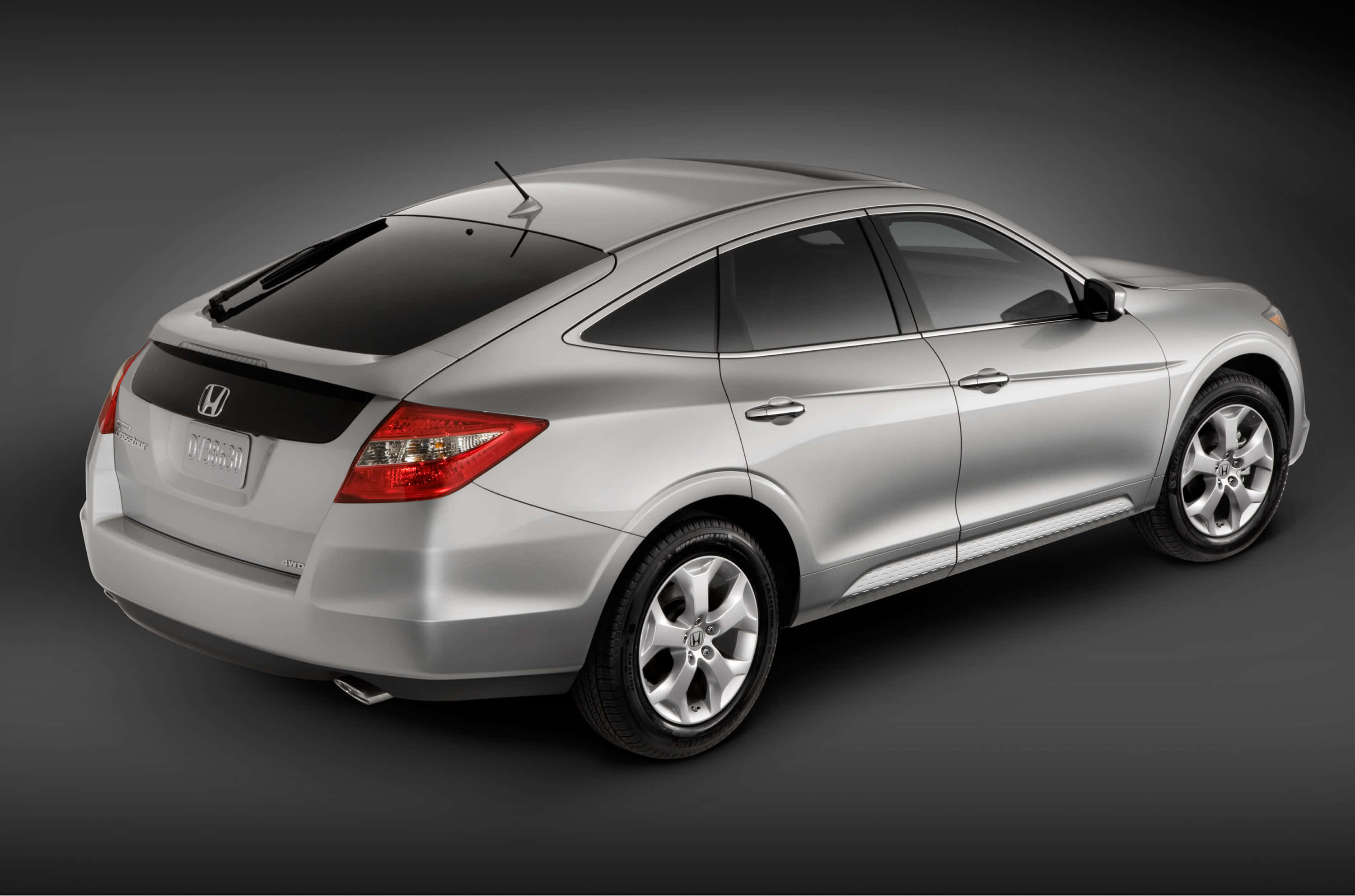 Honda Crosstour 桌布 壁紙 — 一輛時尚的銀色本田雅閣混合動力轎車，在深灰色背景下的工作室拍攝中從後方四分之三角度展示。