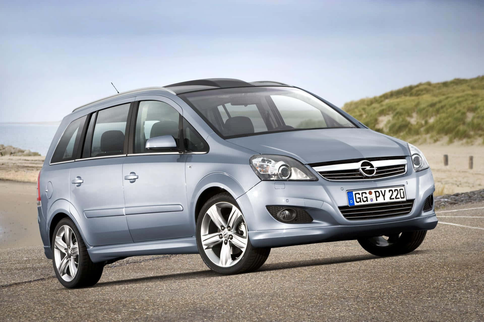 Opel Zafira 桌布 壁紙 — 一架時尚的銀色歐寶Zafira停泊在沿海公路上，背景有沙丘和海洋。