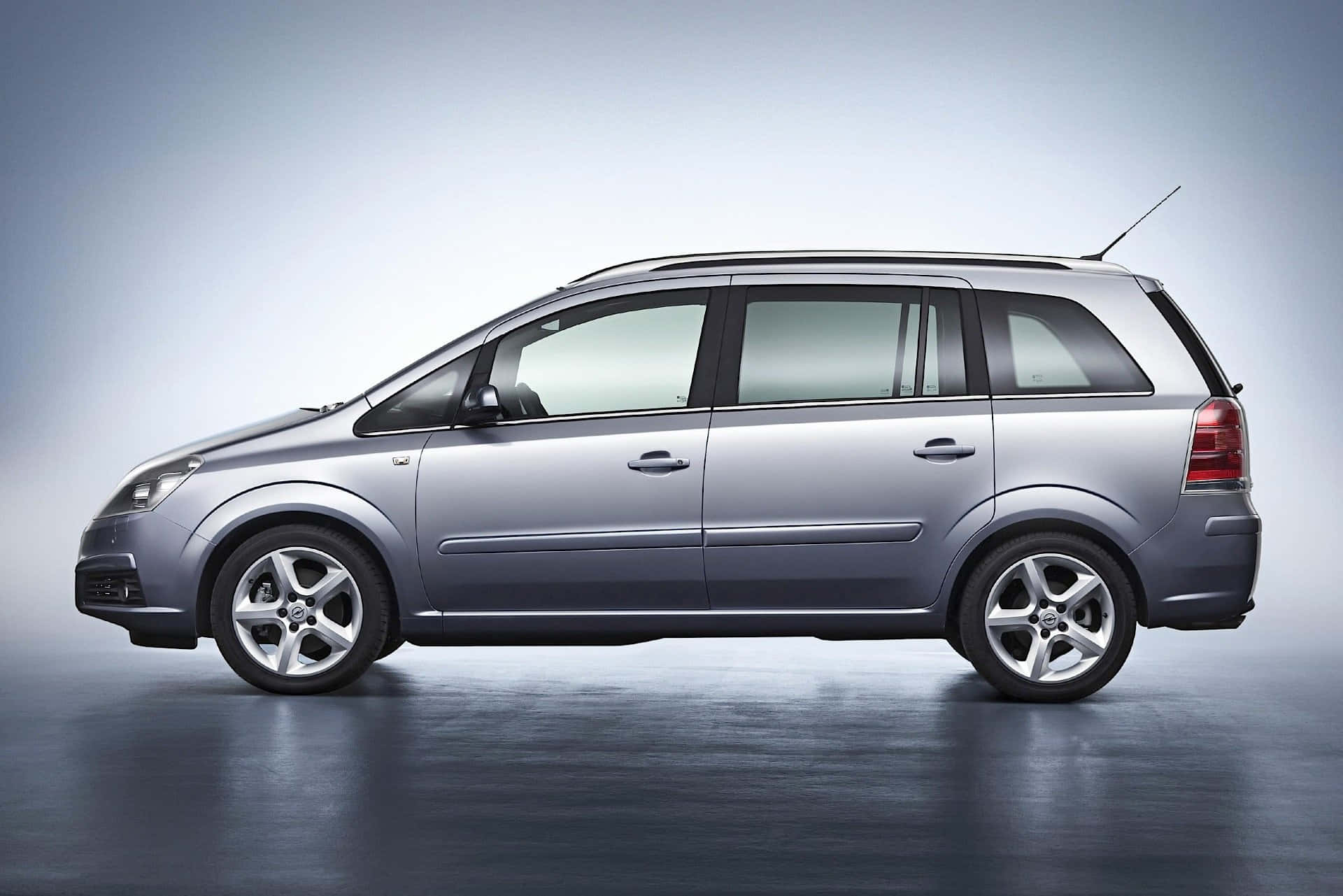 Opel Zafira 桌布 壁紙 — 一輛時尚的銀色旅行車在一個帶有漸變灰色背景和反光地板的攝影棚中展示。