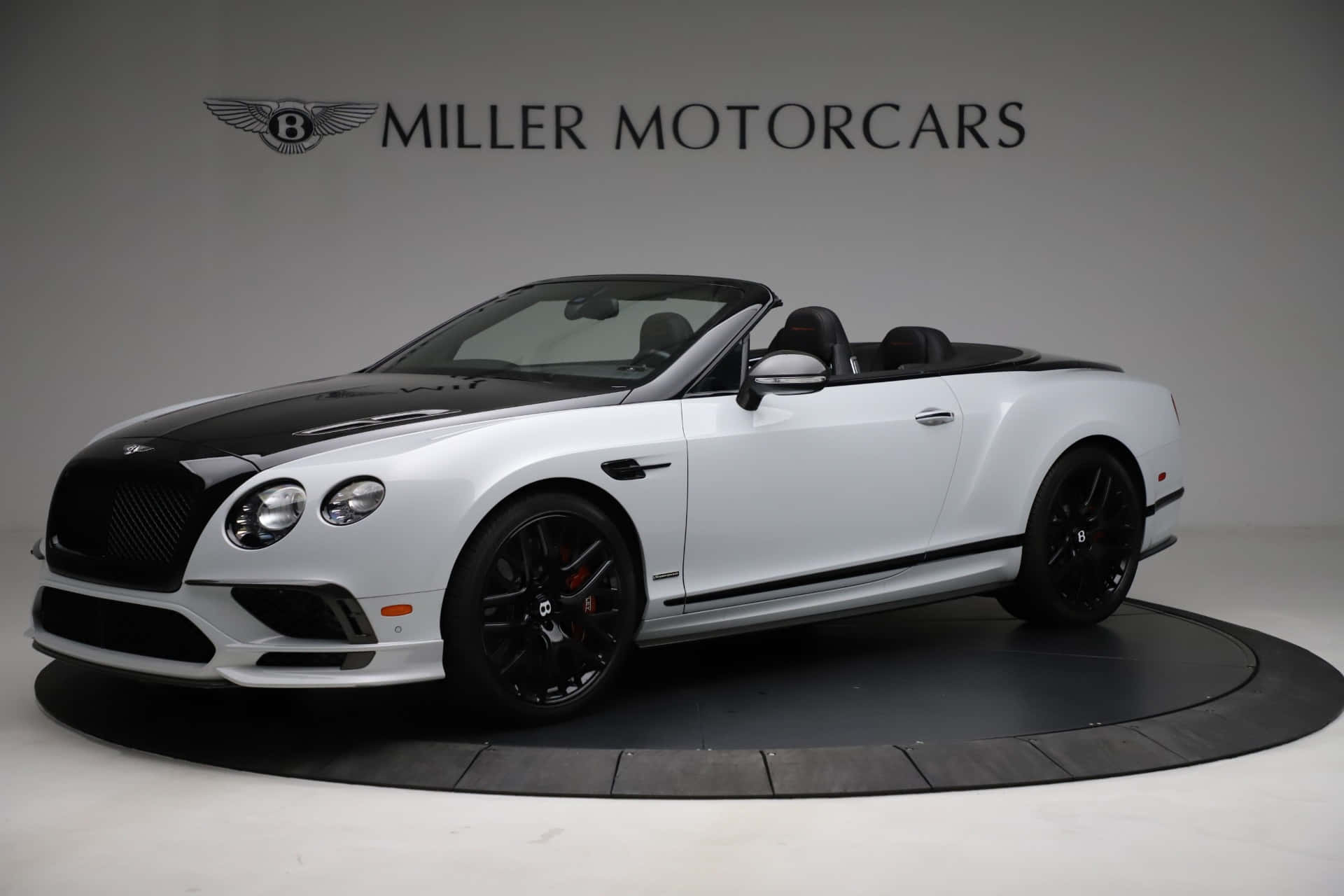 Bentley Continental Supersports 桌布 壁紙 — 一輛時尚的白色和黑色賓利敞篷車配黑色輪圈，在攝影棚燈光下展示於圓形平台上。