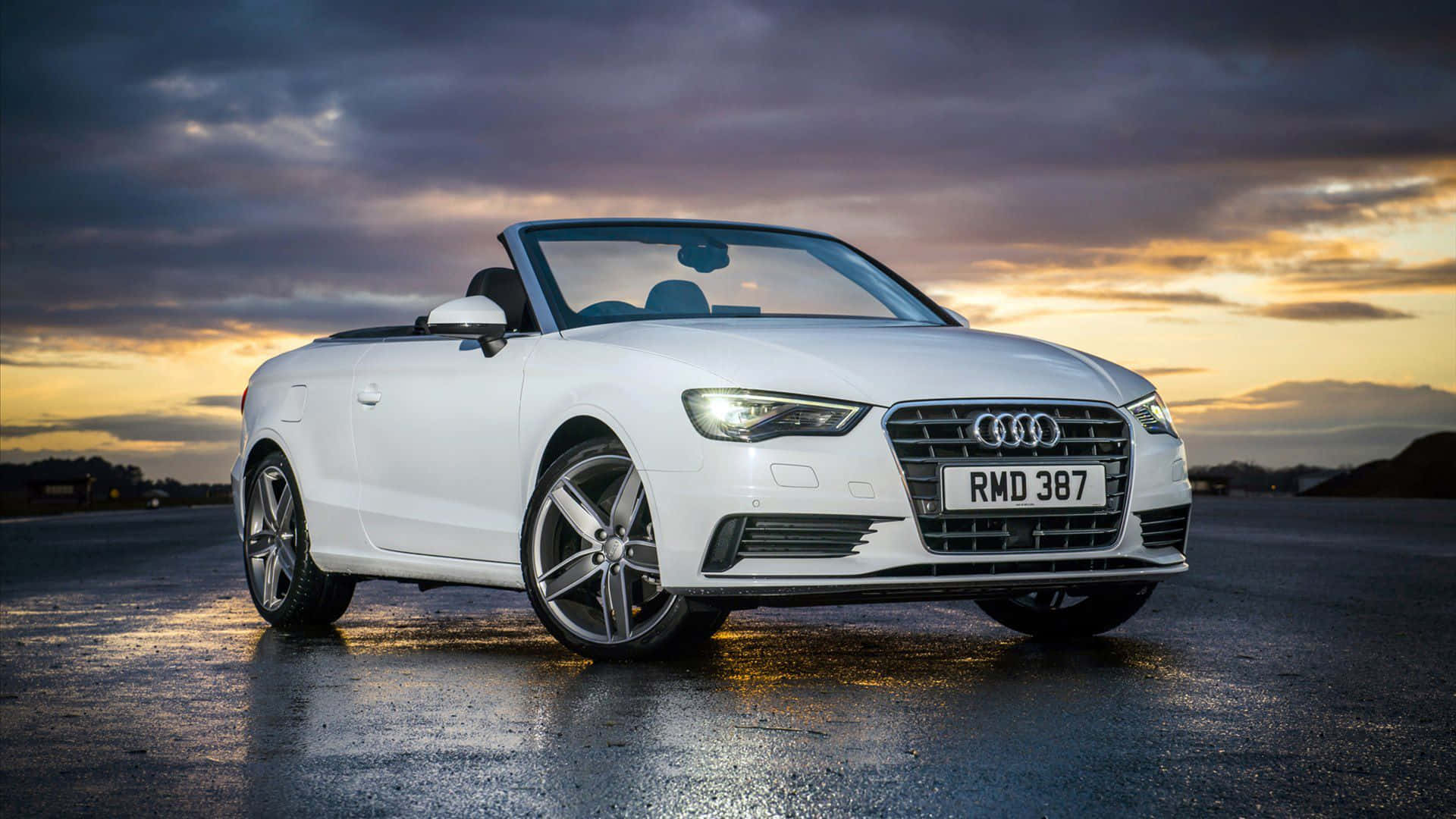 Audi A3 桌布 壁紙 — 一輛時尚的白色奧迪開篷車在橙紫色雲彩的戲劇性日落天空下閃閃發光。