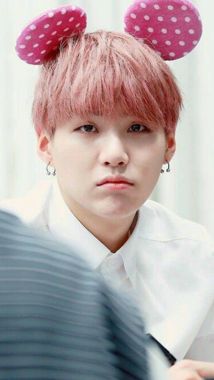 可愛鼠耳 Suga BTS 壁紙 — 一個粉紅色頭髮、戴著波點兔耳的人，穿著白色襯衫，背景柔和模糊。