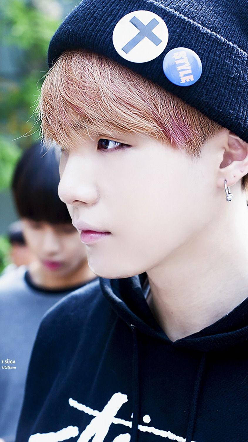 Suga BTS戴針織帽 壁紙 — 年輕男子近距離肖像照，粉紅色頭髮，戴黑色鈕扣冷帽，穿黑色連帽衛衣。