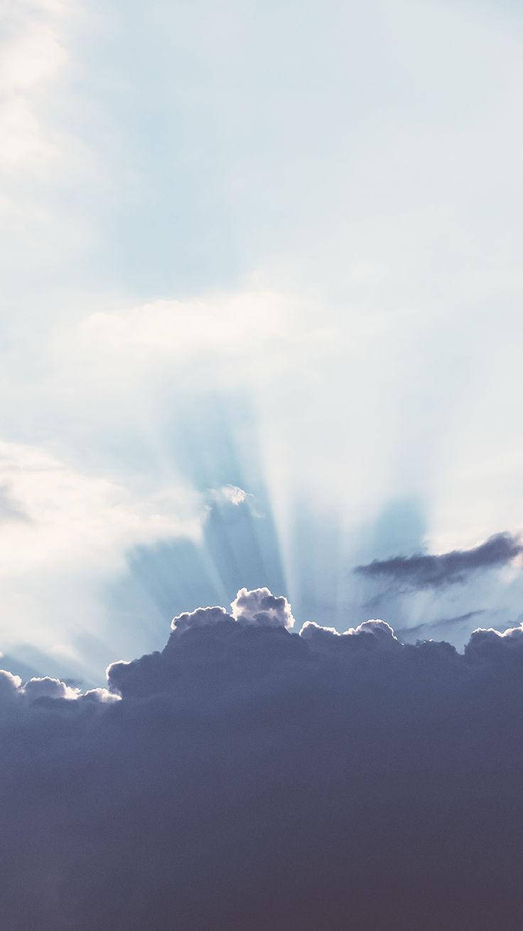 陽光穿過暗雲，在寧靜的藍天中閃耀。