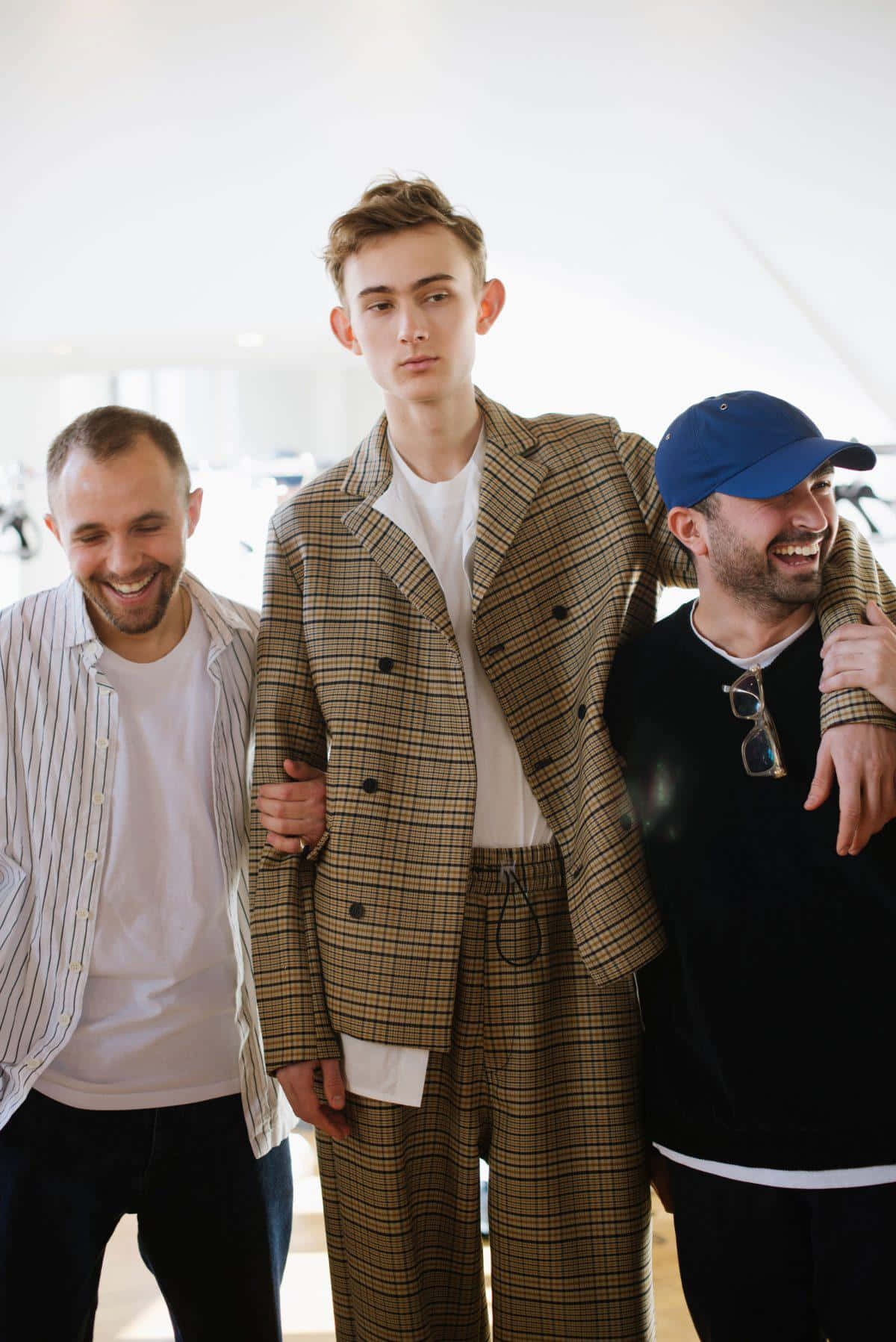 三個男人在明亮的室內環境中一起大笑，穿著休閒和格子服裝。