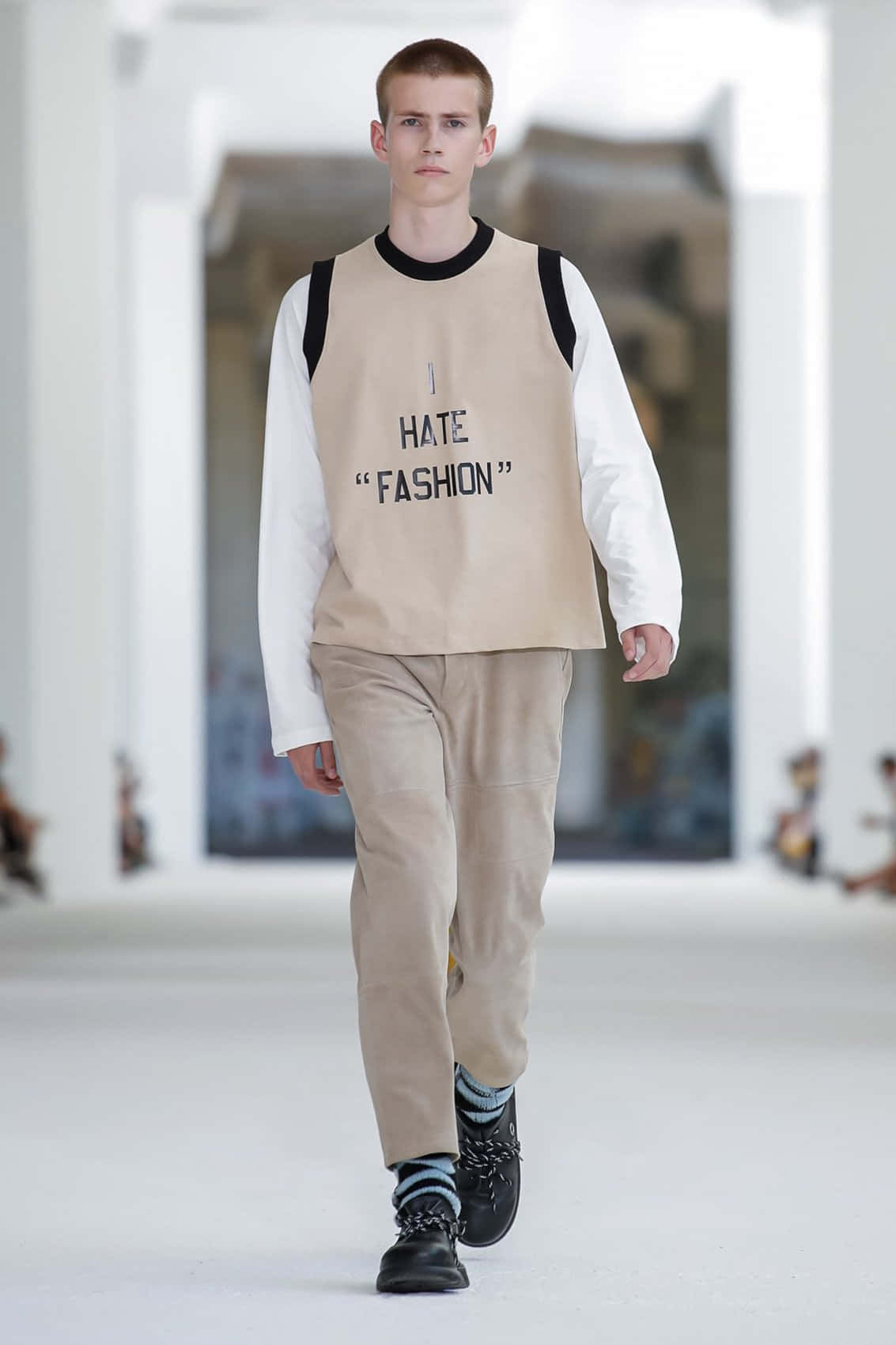 男模特兒身穿印有「I HATE FASHION」字樣的米色背心在T台上走秀。