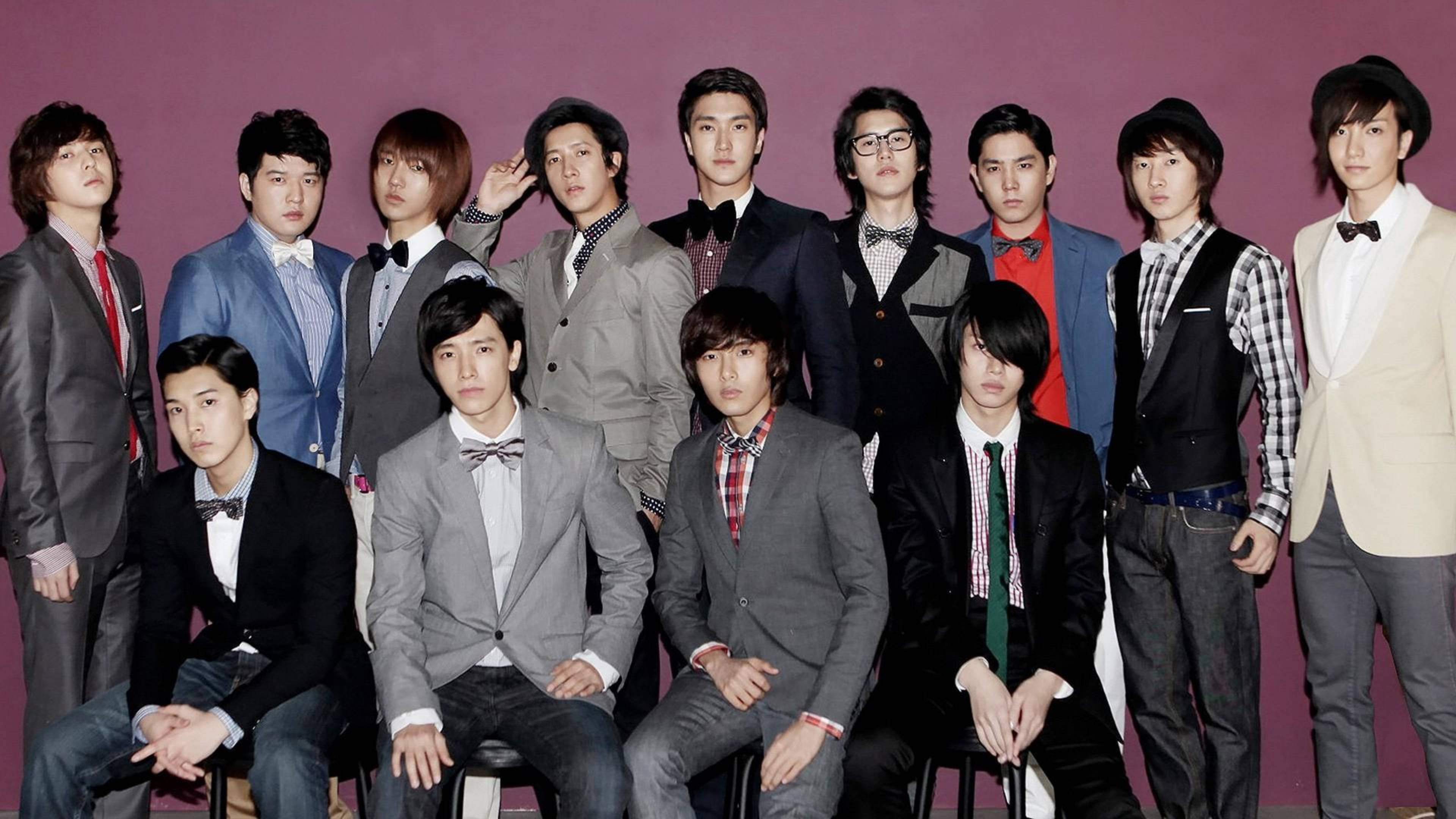 Super Junior蝴蝶結領帶造型 壁紙 — 一群穿著西裝和領結的時尚年輕男子在純紫色攝影棚背景前自信地擺姿勢。