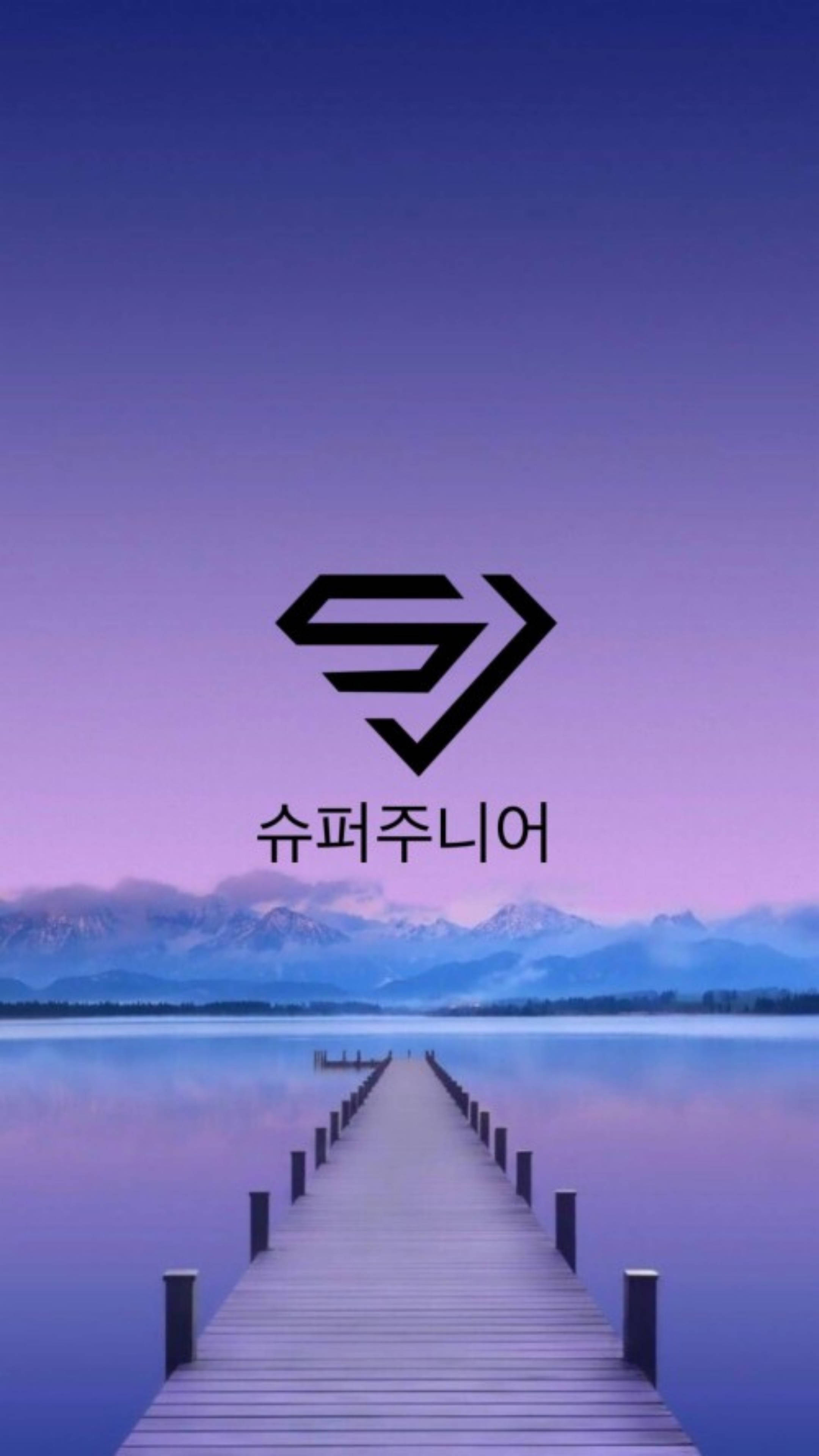 Super Junior 橋樑標誌 壁紙 — 一個木製碼頭延伸到平靜的紫色湖泊中，在暮色天空下，遠處有積雪覆蓋的山脈。