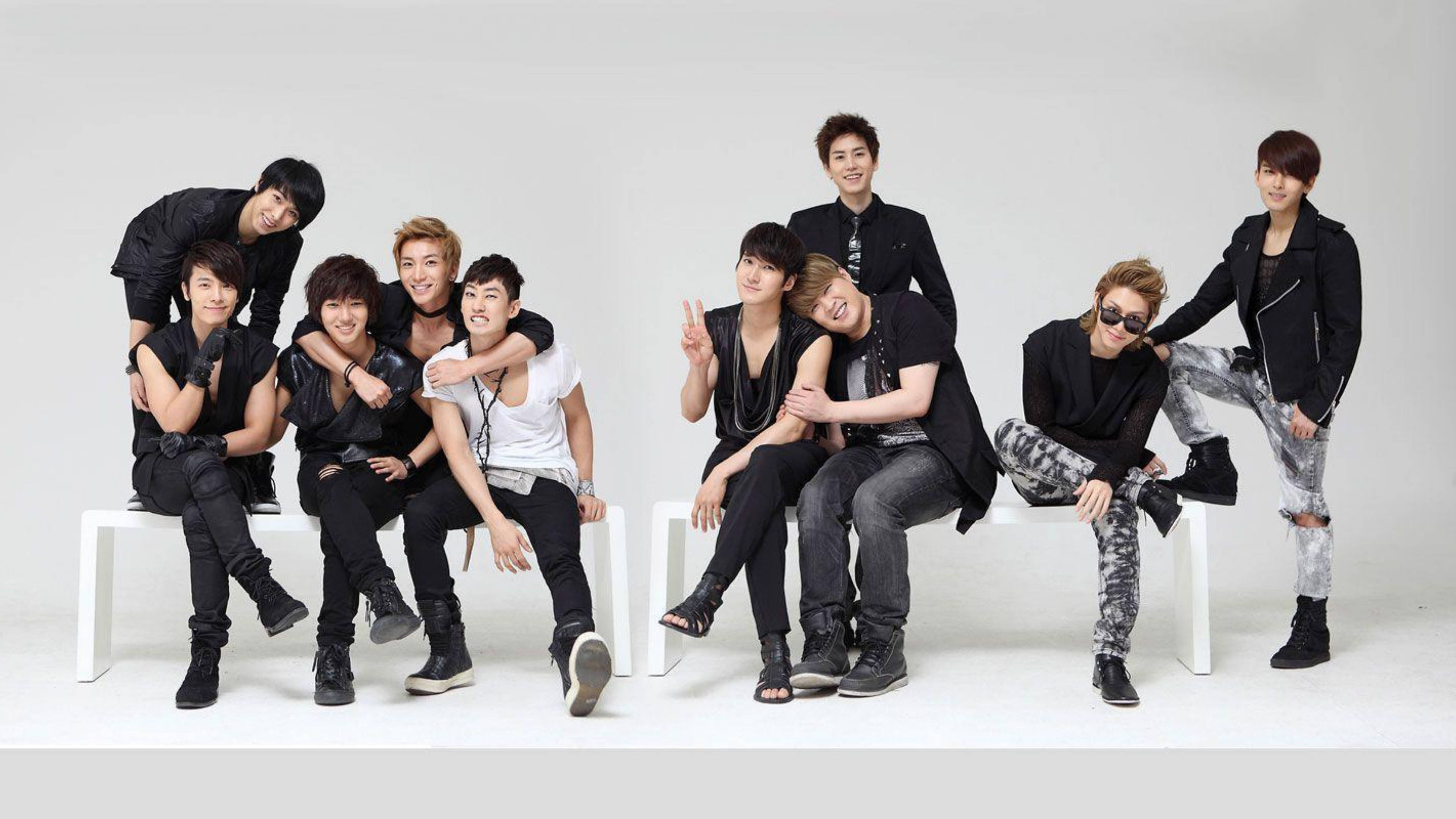 Super Junior 甜蜜時刻 壁紙 — 七位時尚年輕男士身穿黑白服裝，在白色長椅上充滿活力地擺姿勢，背景為純白色。