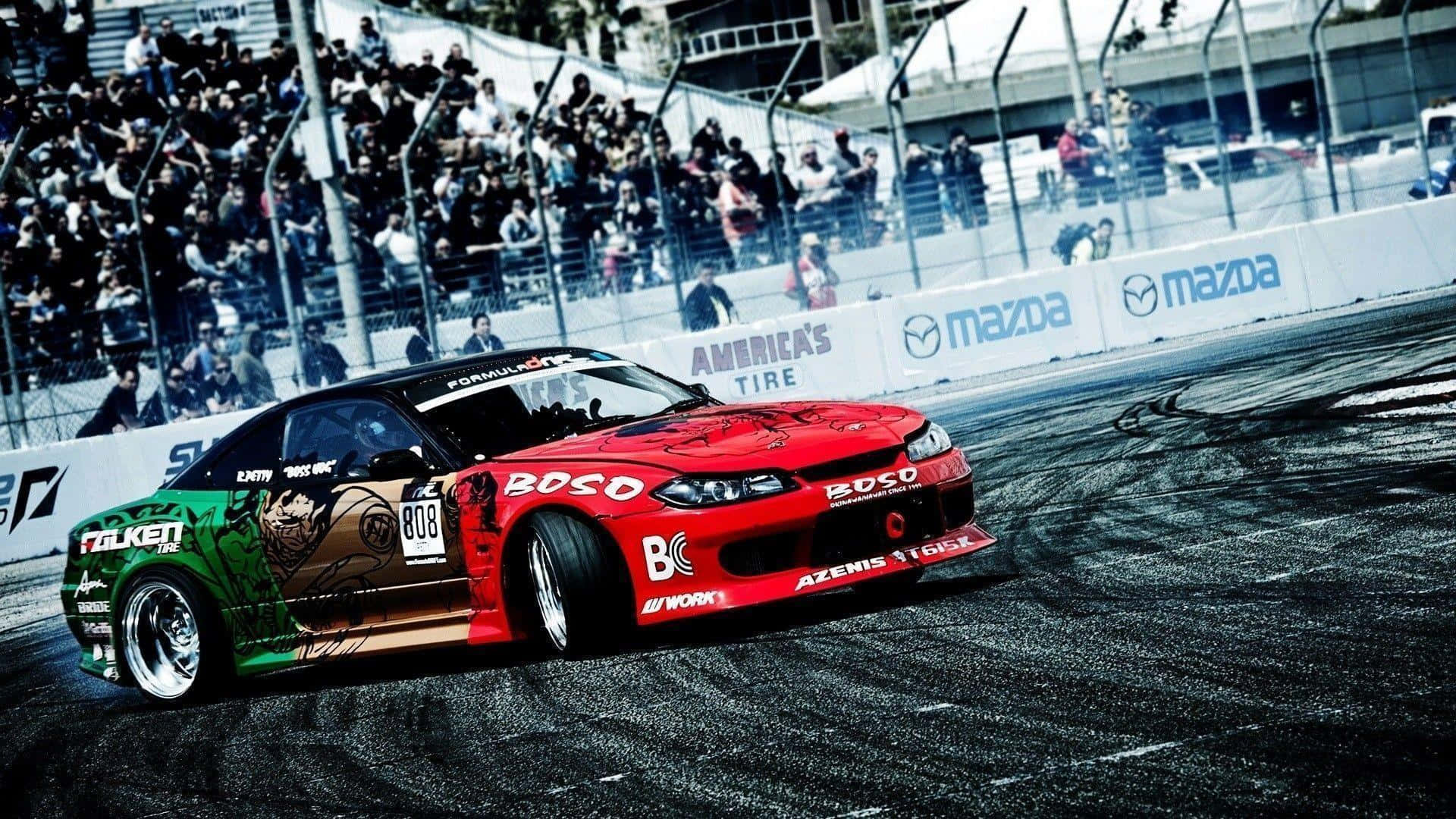 Supra Drift紅色賽車 壁紙 — 一輛帶有醒目圖案的紅綠飄移車在賽道上側滑，觀眾從看台上觀看。
