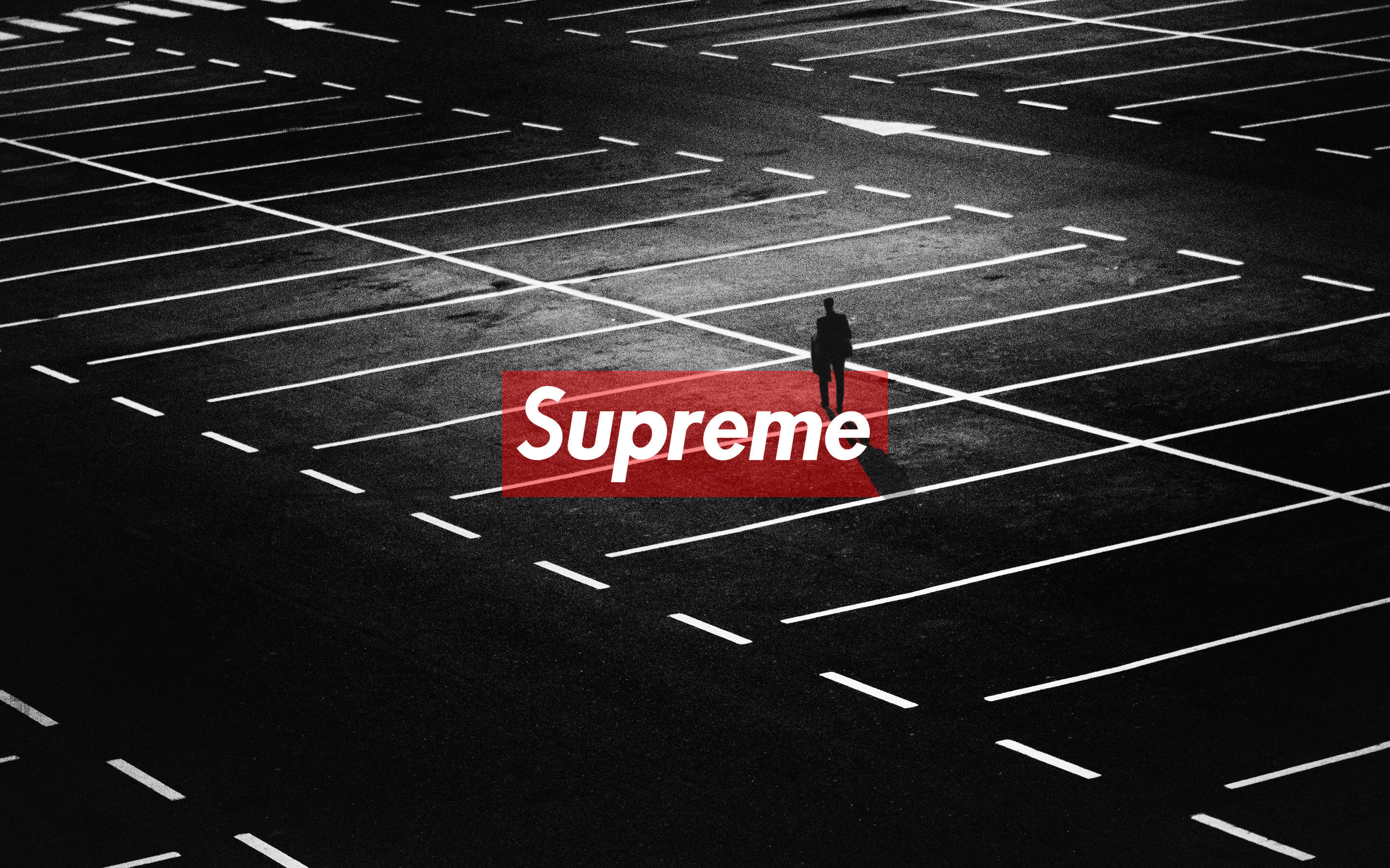 空曠停車場 Supreme筆電 壁紙 — 一個孤獨的身影站在空曠的停車場，在強烈的人造燈光下，帶有醒目的紅色Supreme標誌疊加。