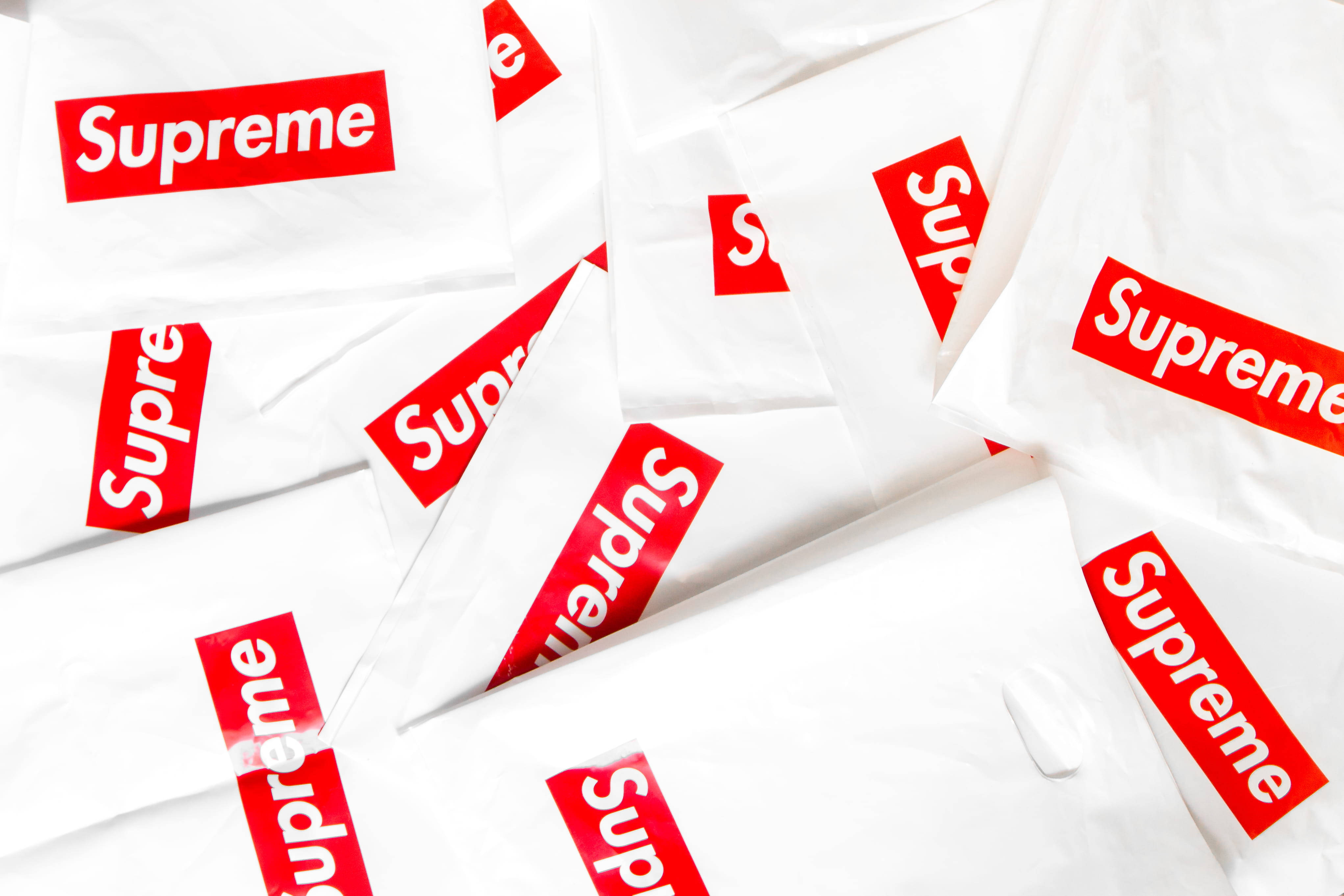 紙袋 Supreme 筆記本電腦壁紙 壁紙 — 一堆皺巴巴的白色Supreme購物袋，表面散落著大膽的紅色標誌。